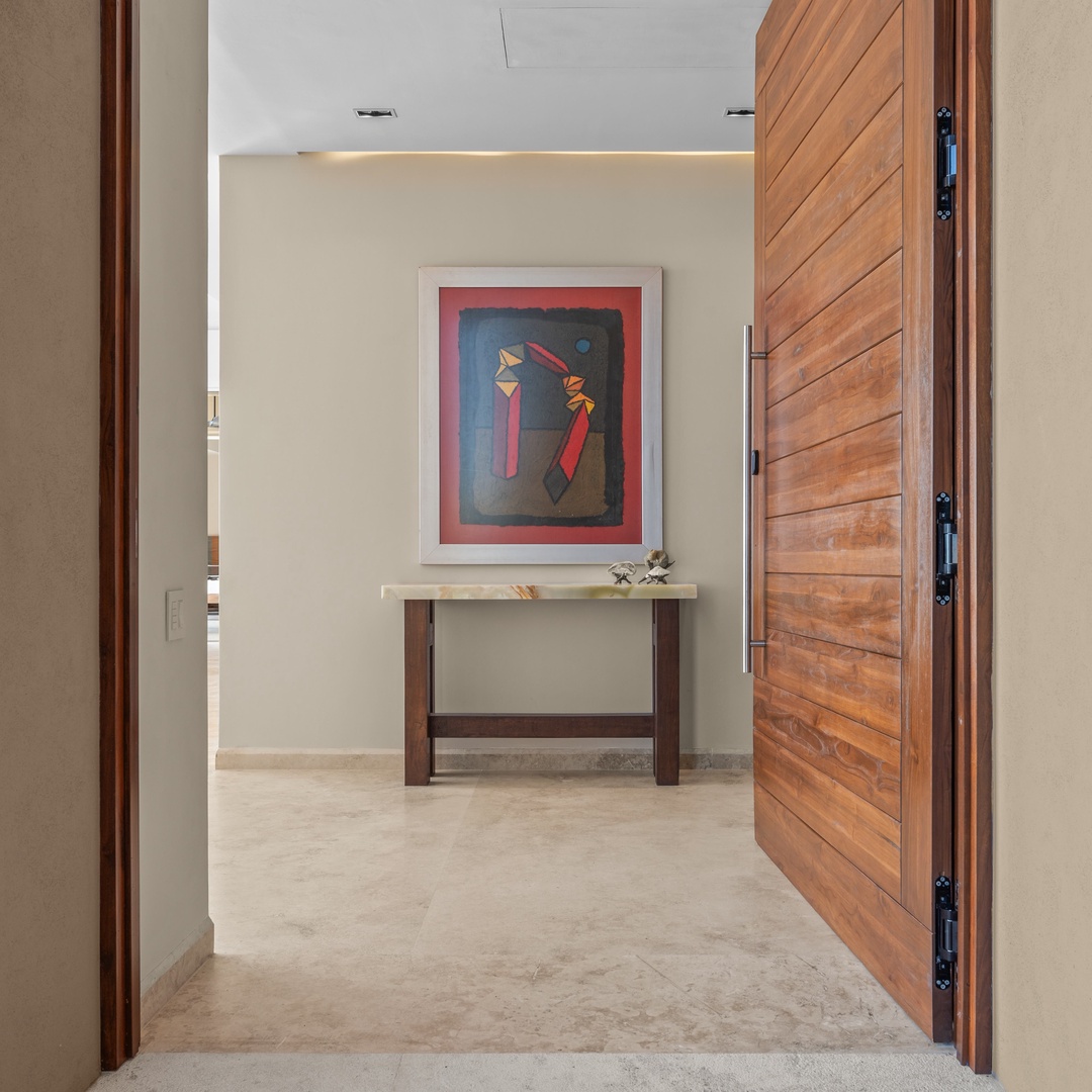 Warm wood doors open to reveal an inviting entryway with contemporary artwork and thoughtful lighting, welcoming you into your serene retreat.