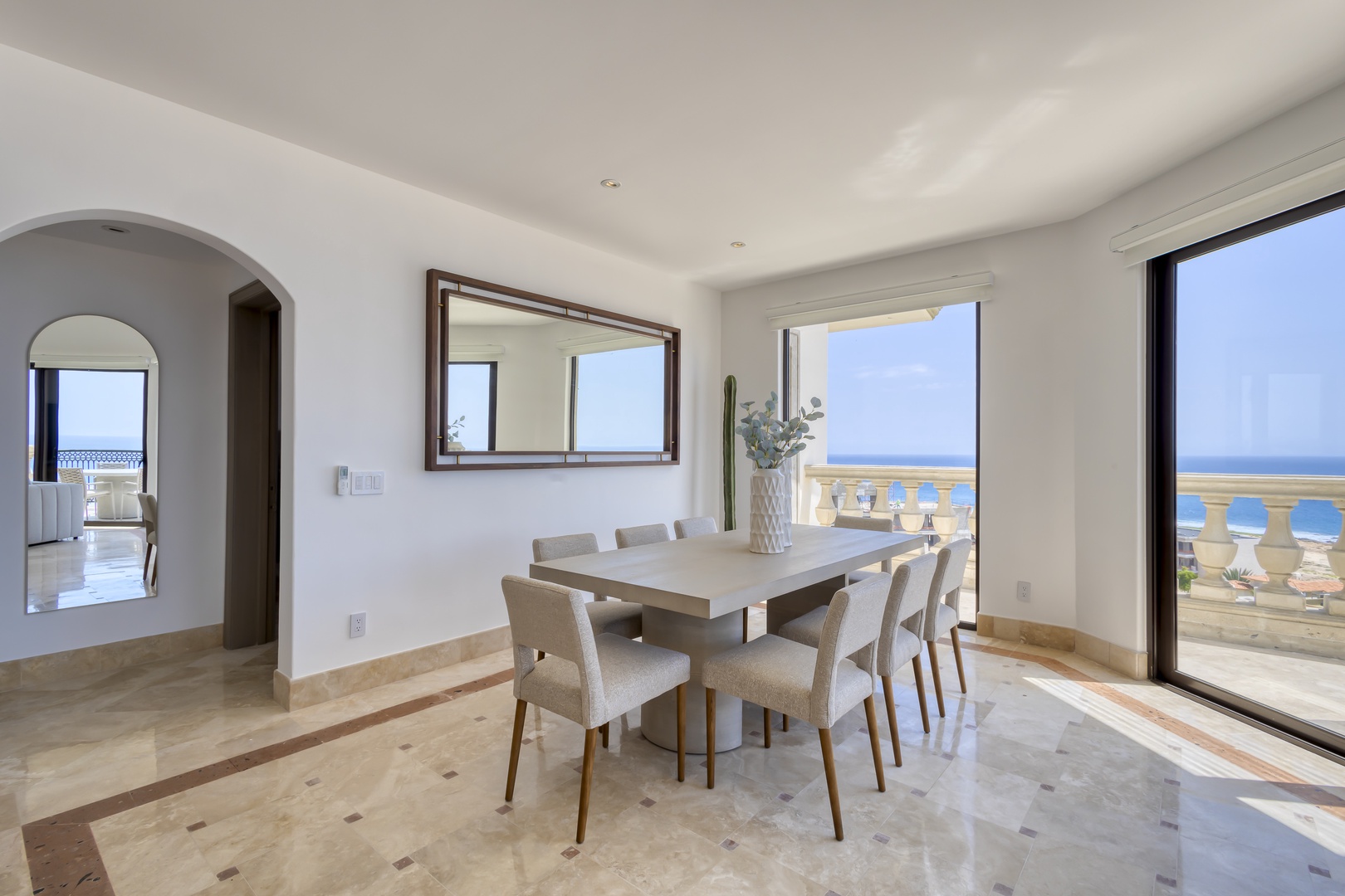 Gather around this elegant dining table where meals become memories, with ocean breezes drifting through open doors to your private terrace overlooking endless blue waters.