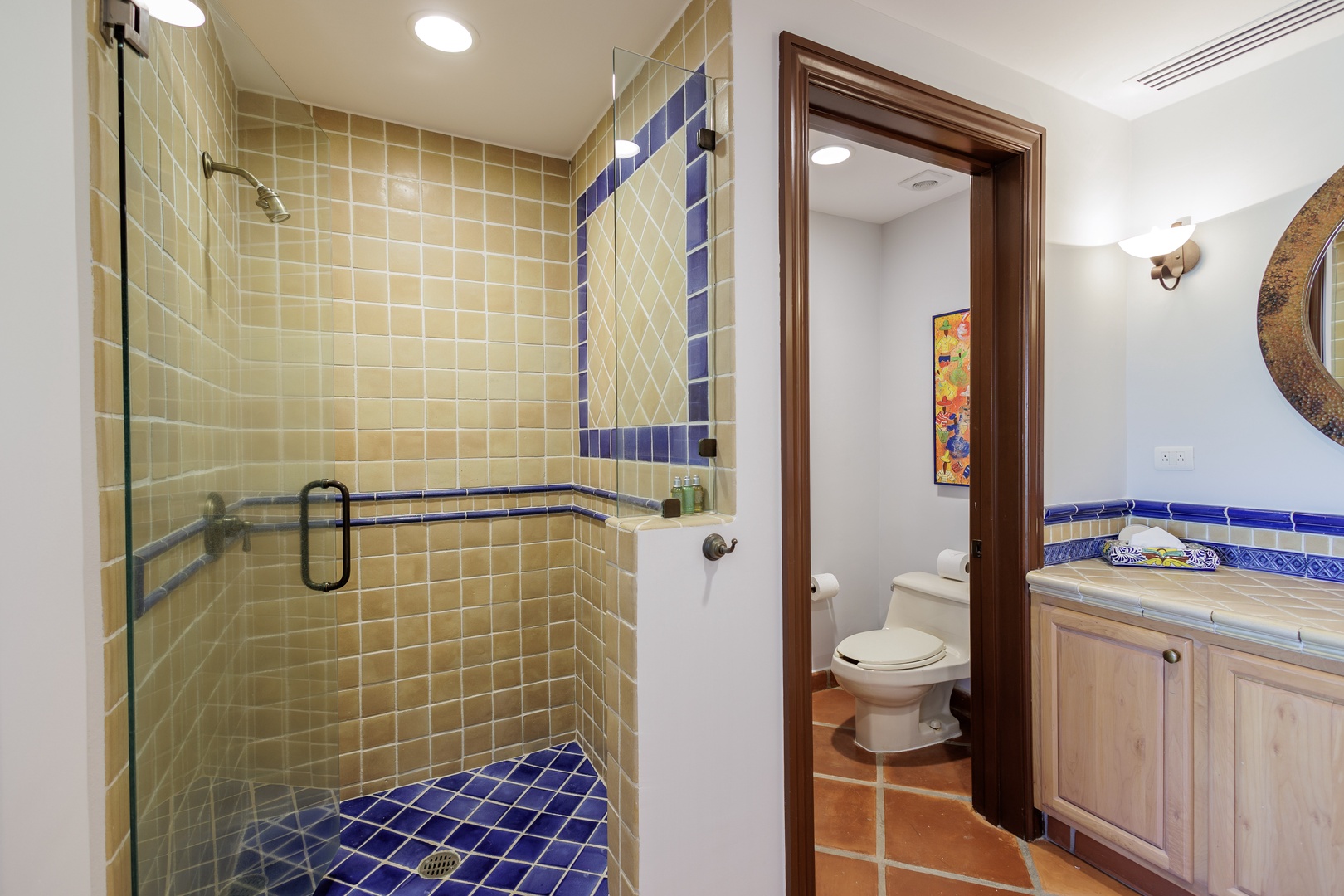 Your private bathroom features a spacious walk-in shower with striking blue and cream tile accents, plus all the essentials for a refreshing start to your day.