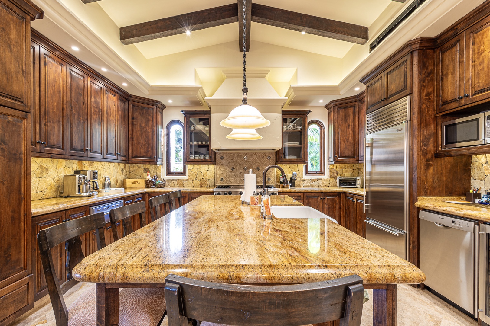 Your gourmet kitchen features rich wood cabinetry, gleaming granite countertops, and top-tier appliances. Prepare memorable meals under soaring beamed ceilings in this elegant, fully-equipped culinary space.