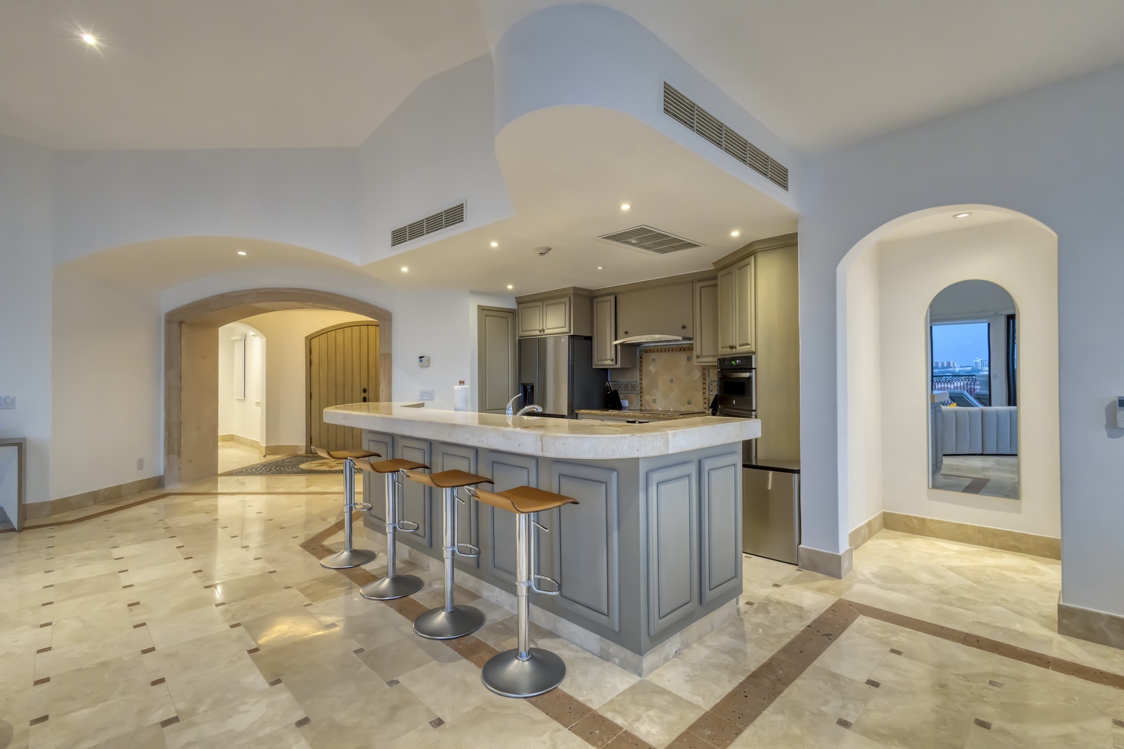 Your elegant kitchen awaits with a spacious island, modern appliances, and sophisticated archways leading to stunning views—perfect for preparing meals and entertaining in style.