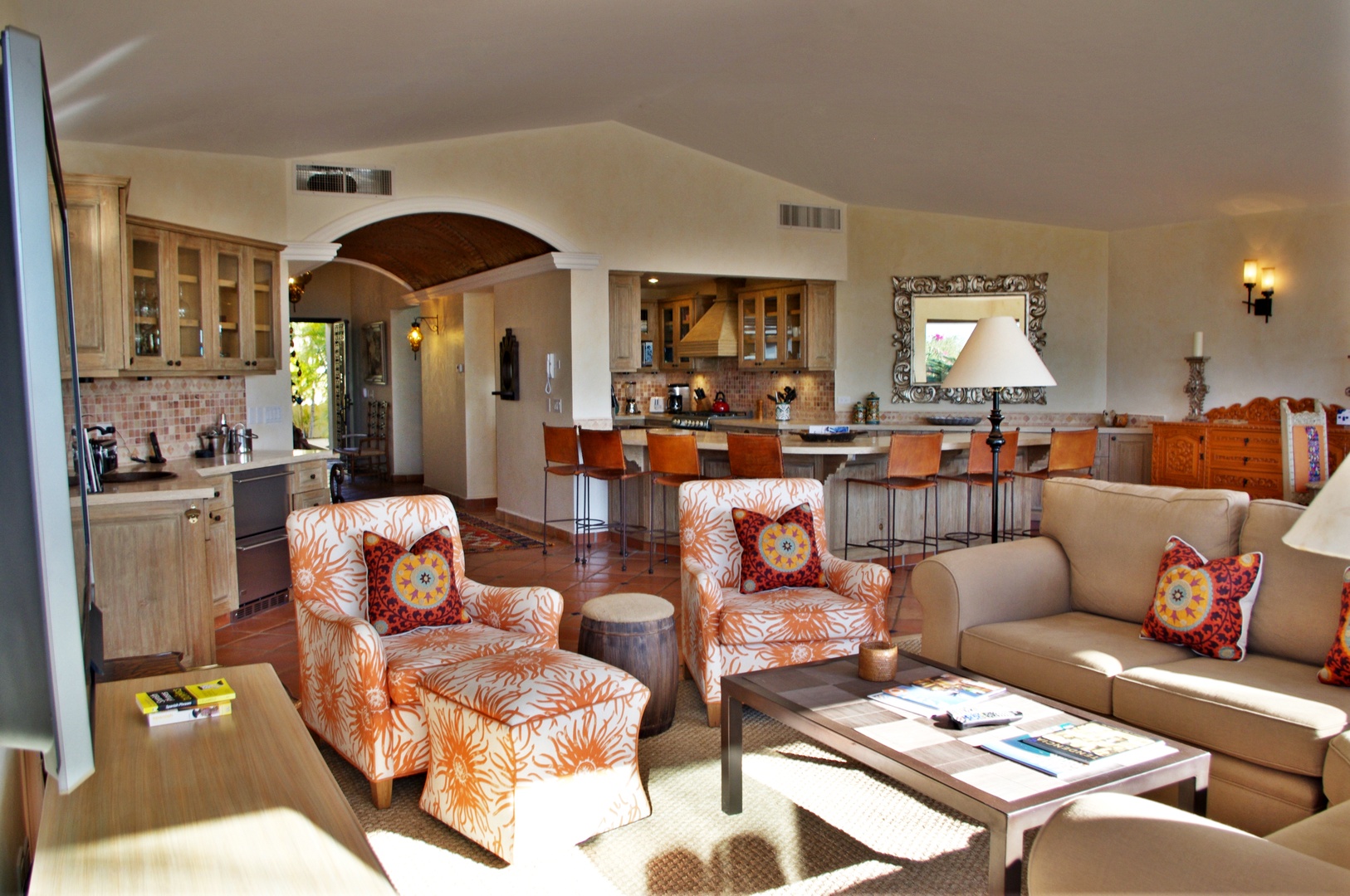 Settle into your sun-drenched living space where vibrant seating invites relaxation while you admire elegant arches framing a gourmet kitchen designed for memorable gatherings.