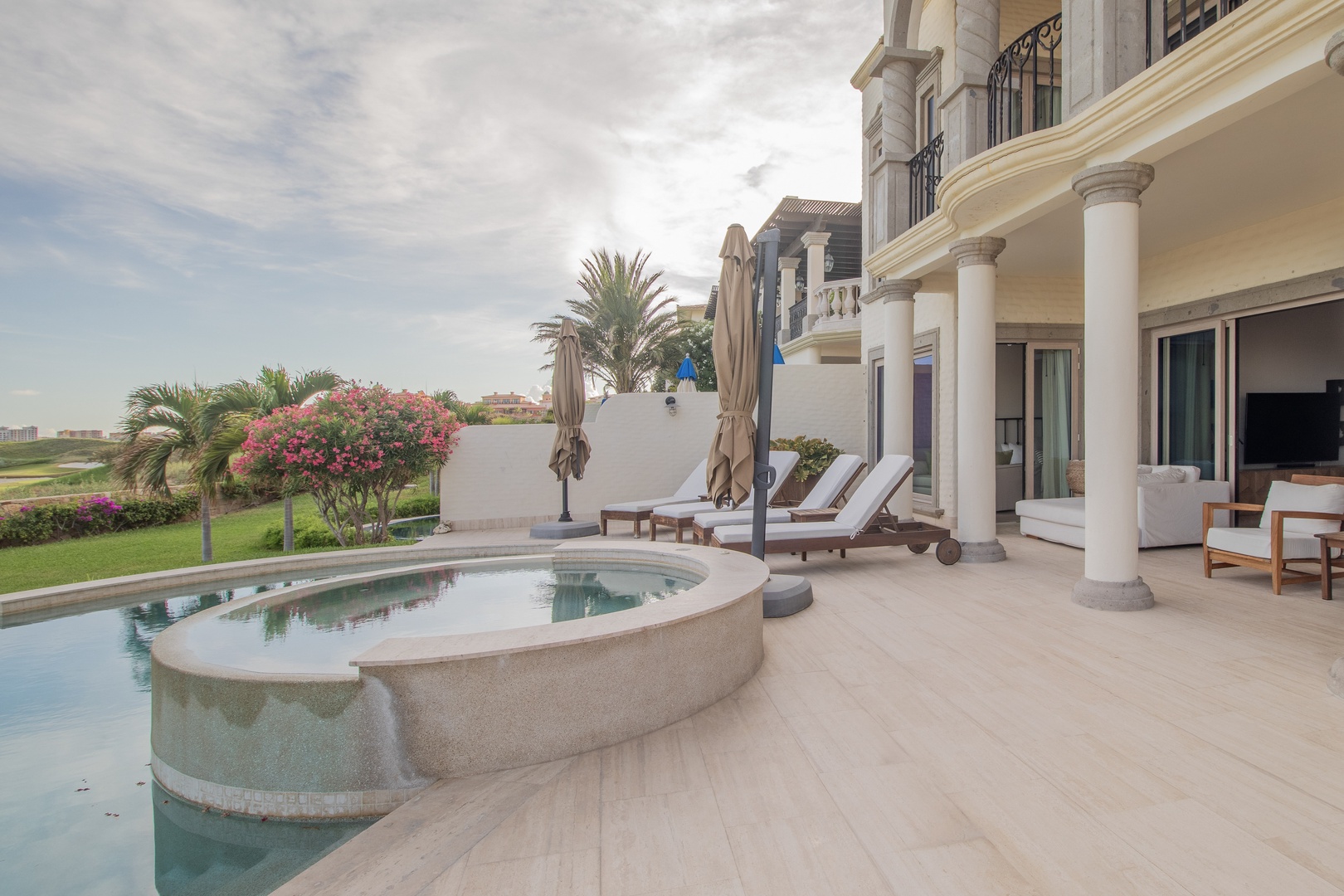 Elegant covered terrace with a private plunge pool, lush tropical gardens, and serene golf course vistas surrounding this luxurious coastal property.