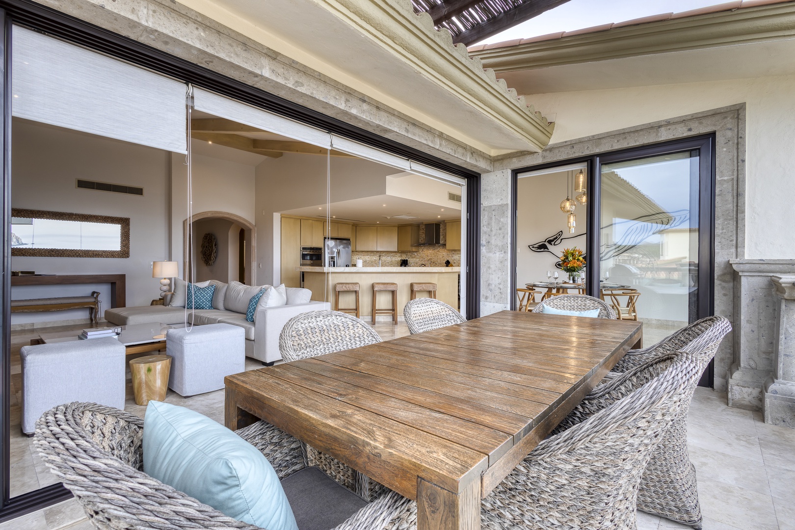 Your covered terrace invites you to dine al fresco at the gorgeous wooden table, with open-air access seamlessly blending indoor elegance and coastal comfort.