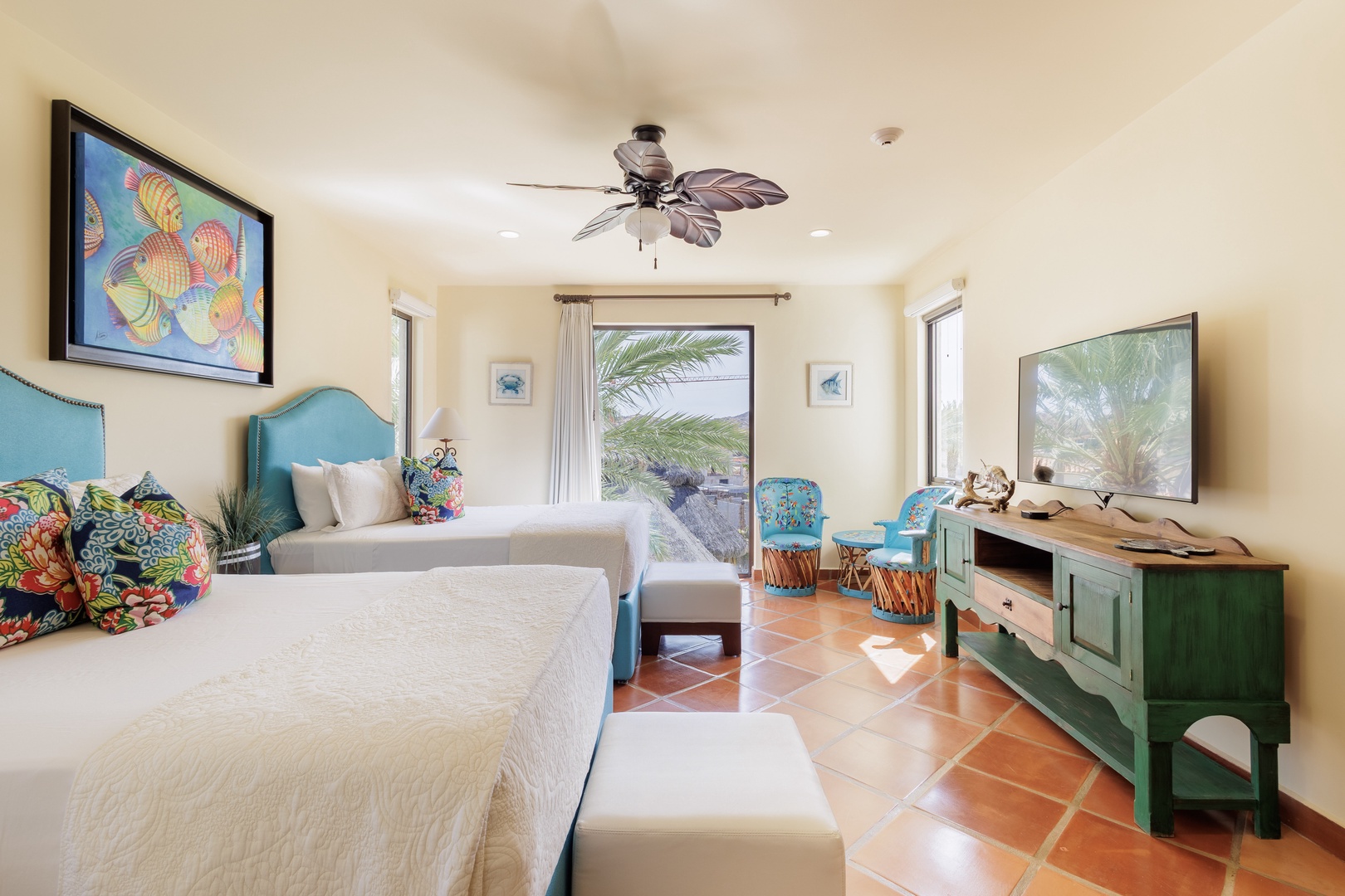 Unwind in your coastal-inspired bedroom with tropical ceiling fan, crisp white linens, and vibrant island décor. French doors open to outdoor views, bringing breezy relaxation right to your doorstep.