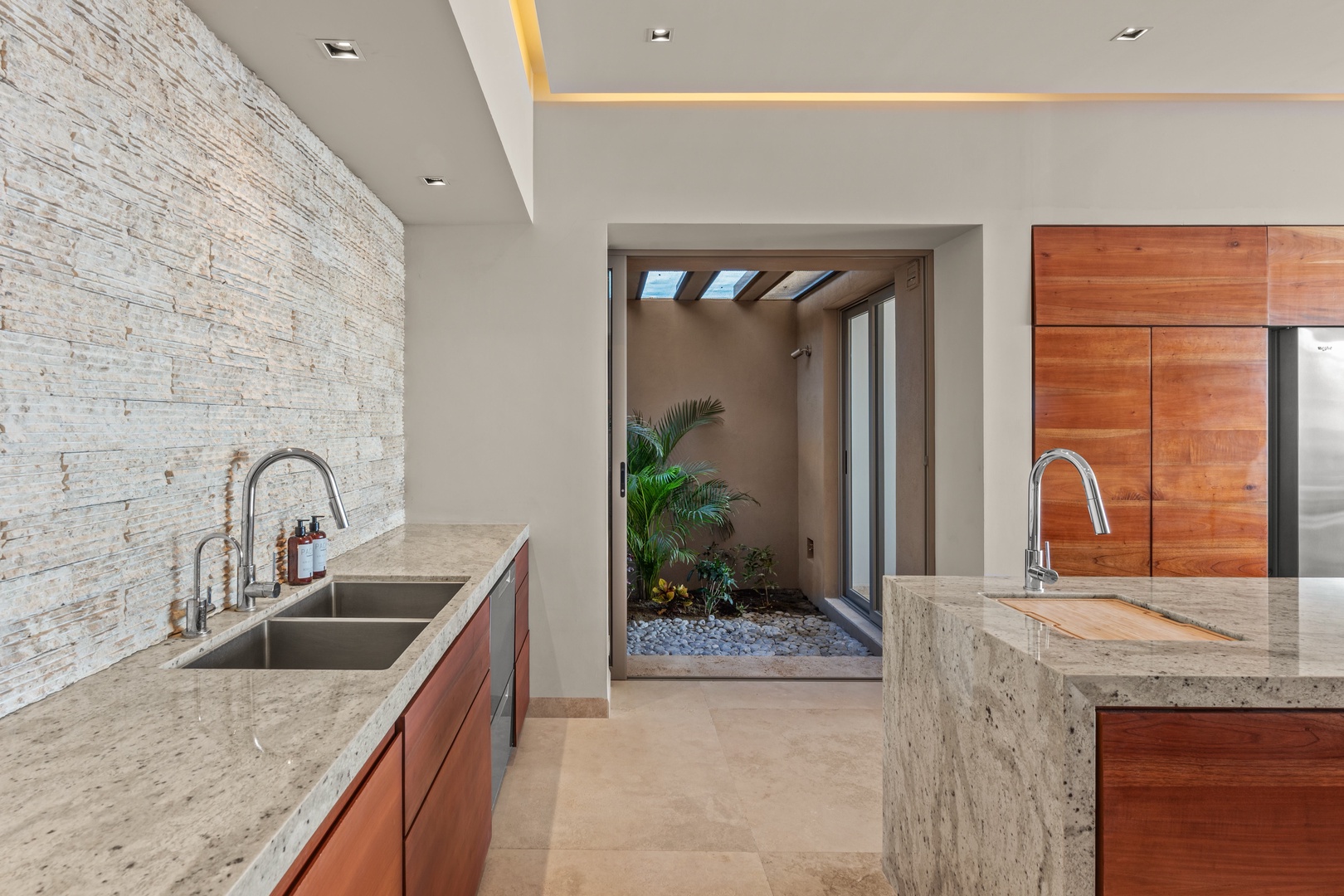 Your gourmet kitchen features elegant marble counters, dual prep areas, and warm wood cabinetry—perfect for crafting memorable meals while enjoying serene courtyard views.
