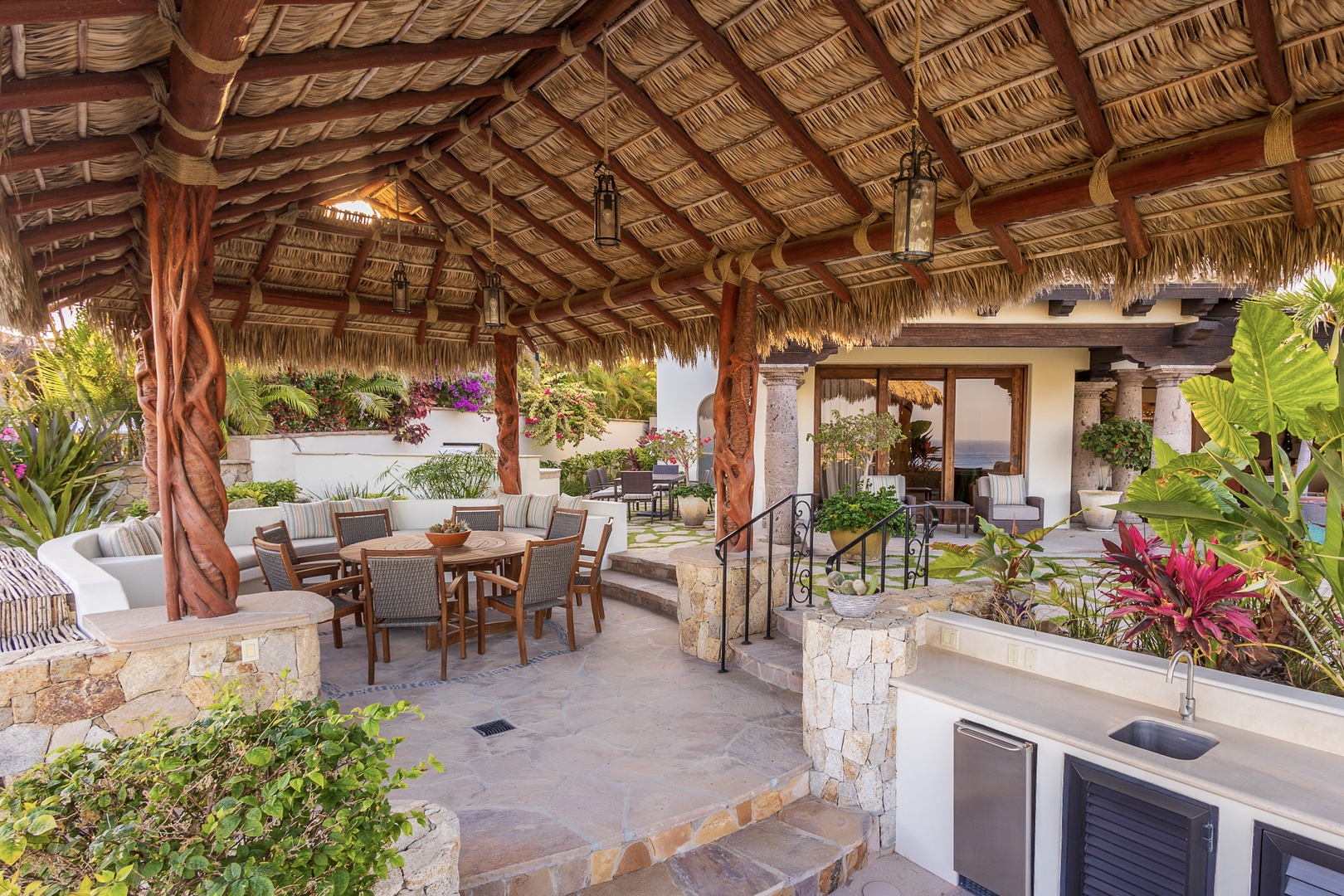 Relax under the palapa-style roof, where tropical breezes drift through your outdoor dining and lounge area. Lush gardens, warm stone accents, and an inviting kitchen await your meals and conversations.