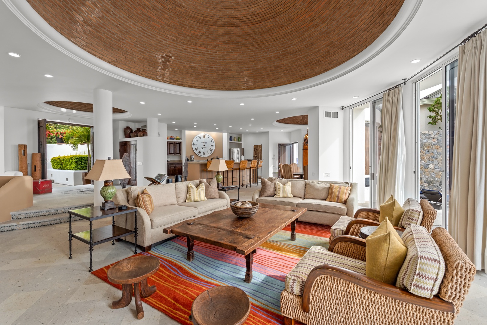 Relax in this stunning open-concept living space featuring a dramatic domed brick ceiling, plush sectional seating, and vibrant Mexican textiles.