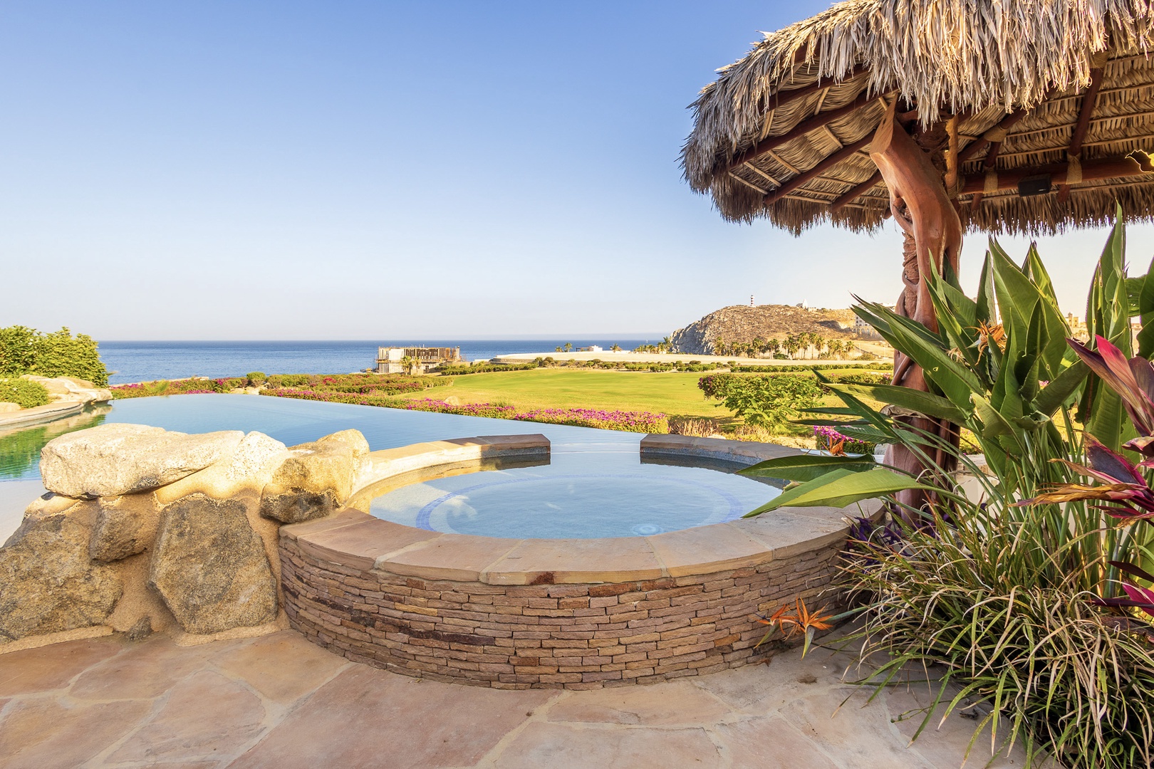 Soak in your private hot tub beneath a thatched palapa, gazing across lush gardens to the sparkling sea beyond—your perfect coastal retreat awaits.