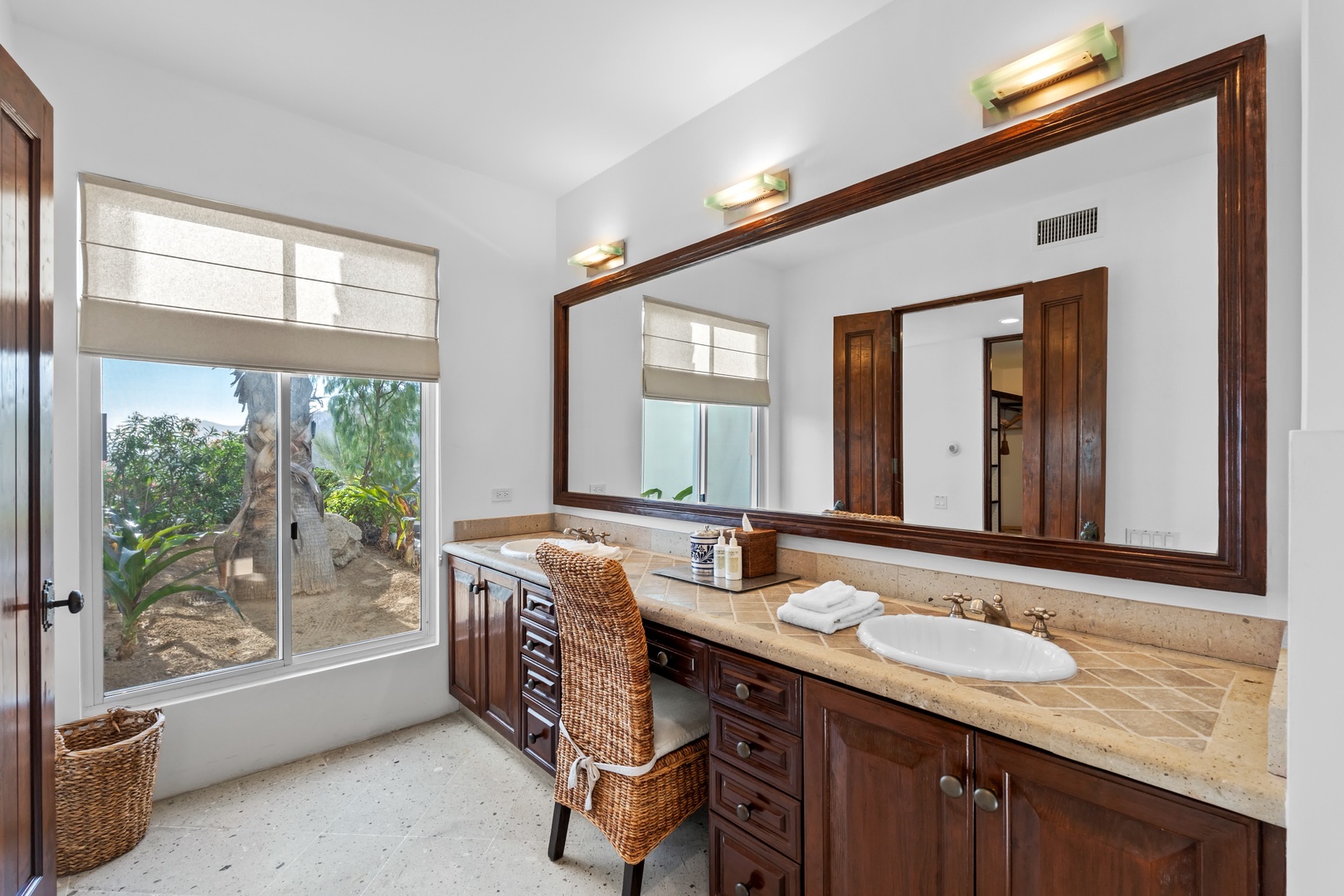 Unwind in your elegant bathroom with warm wood vanity, natural stone counters, and peaceful garden views through your private window.