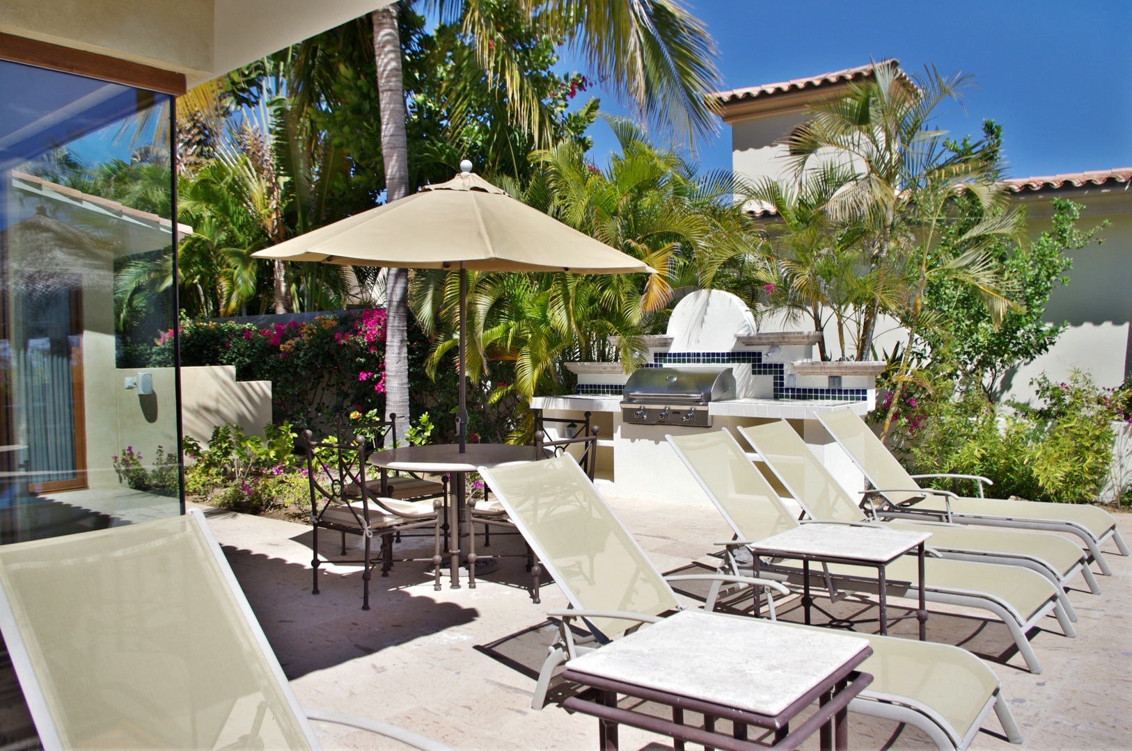 Soak up the sun on your private loungers, then gather at the shaded table for a grilled meal in your lush tropical patio, complete with BBQ and vibrant greenery.