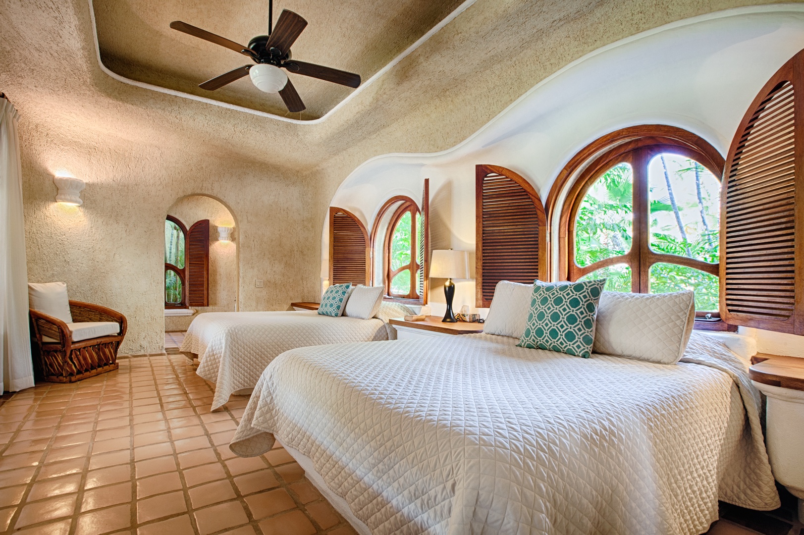 Sink into comfort in your tropical sanctuary with twin beds, elegant arches, and garden views creating the perfect retreat.