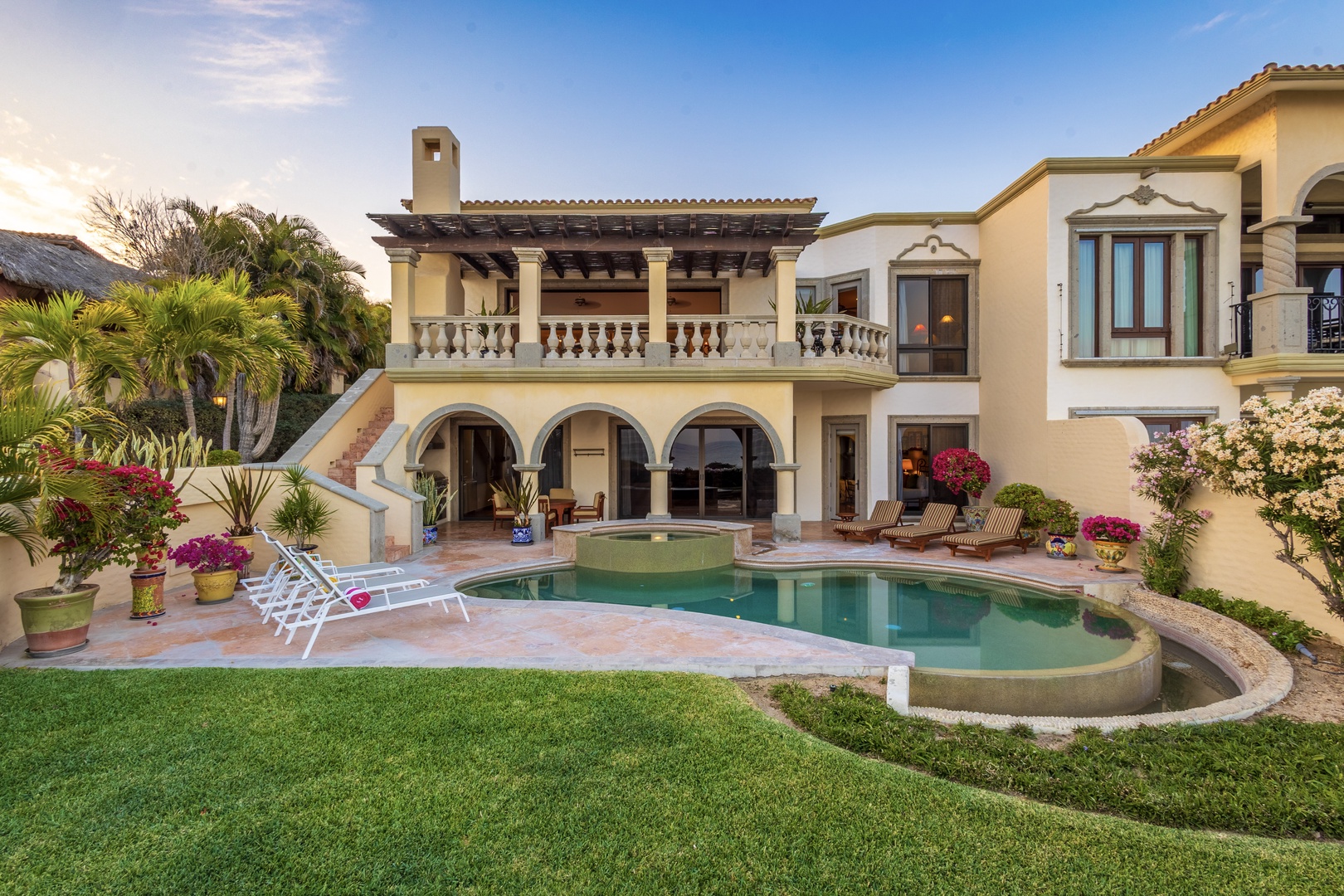 Mediterranean-style villa features arched courtyard entrance, private pool with spa, and lush tropical gardens—perfect for relaxing under warm skies.