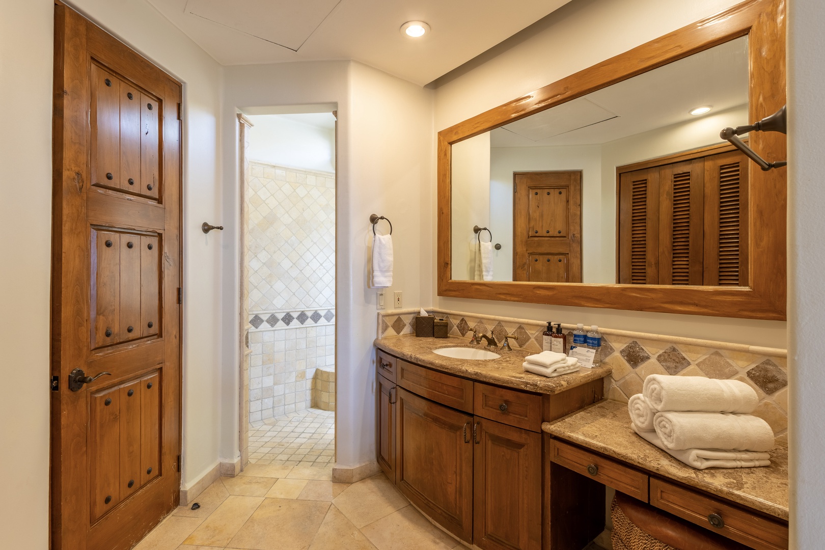 Step into your beautifully appointed bathroom where warm wood accents and granite counters create a welcoming retreat, complete with fluffy towels awaiting your arrival.