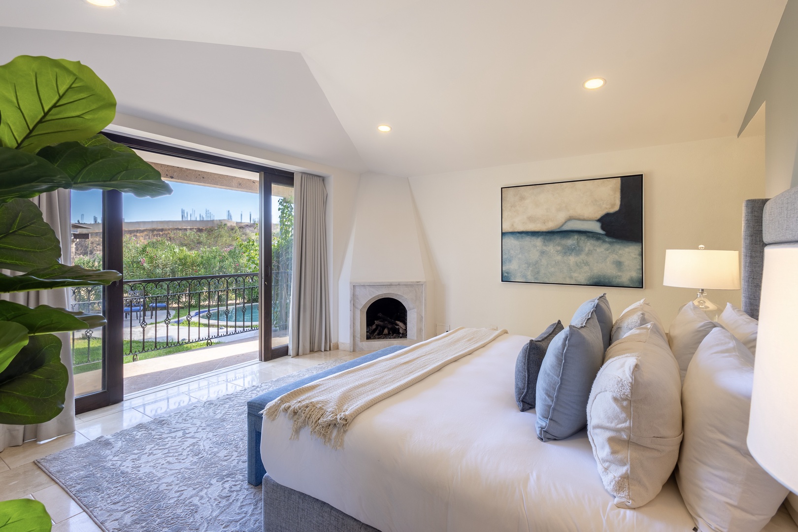 Sink into this plush bed with layers of soft pillows and gaze through your private balcony doors at the sparkling pool and lush gardens beyond. A cozy fireplace and modern art complete your serene retreat.
