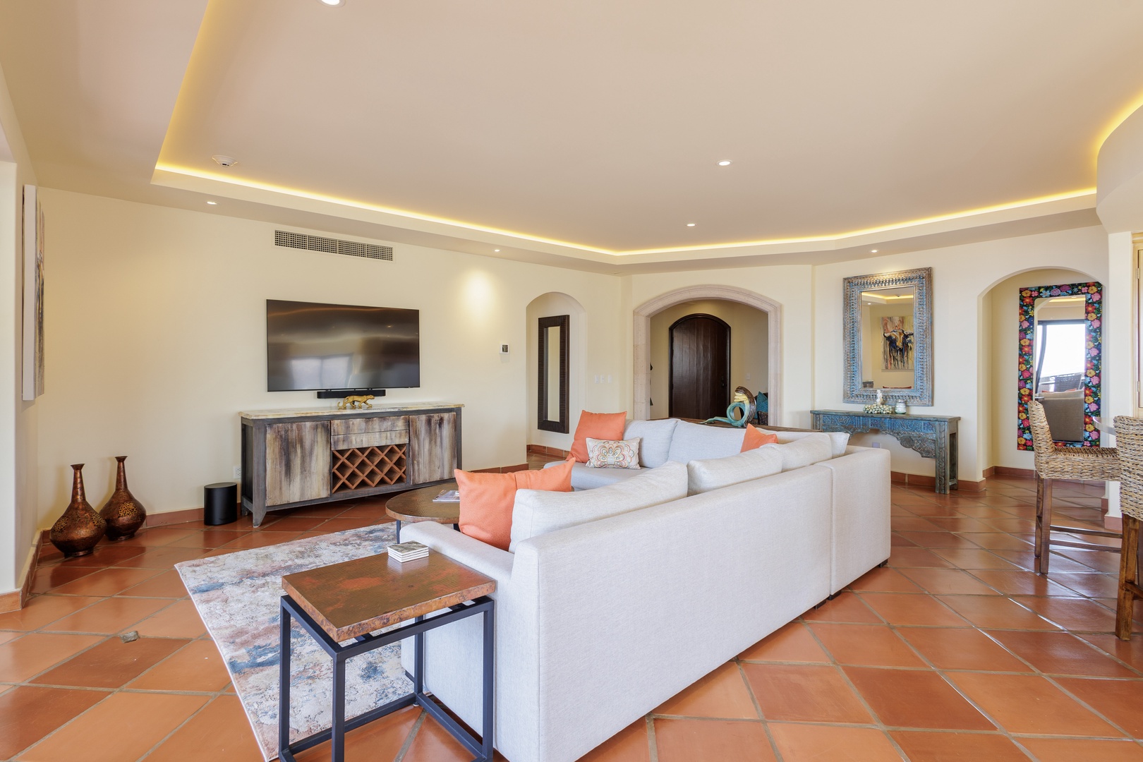 Sink into plush comfort in your spacious living room, where warm terracotta tiles, soft ambient lighting, and charming arched doorways create a welcoming retreat for relaxation.