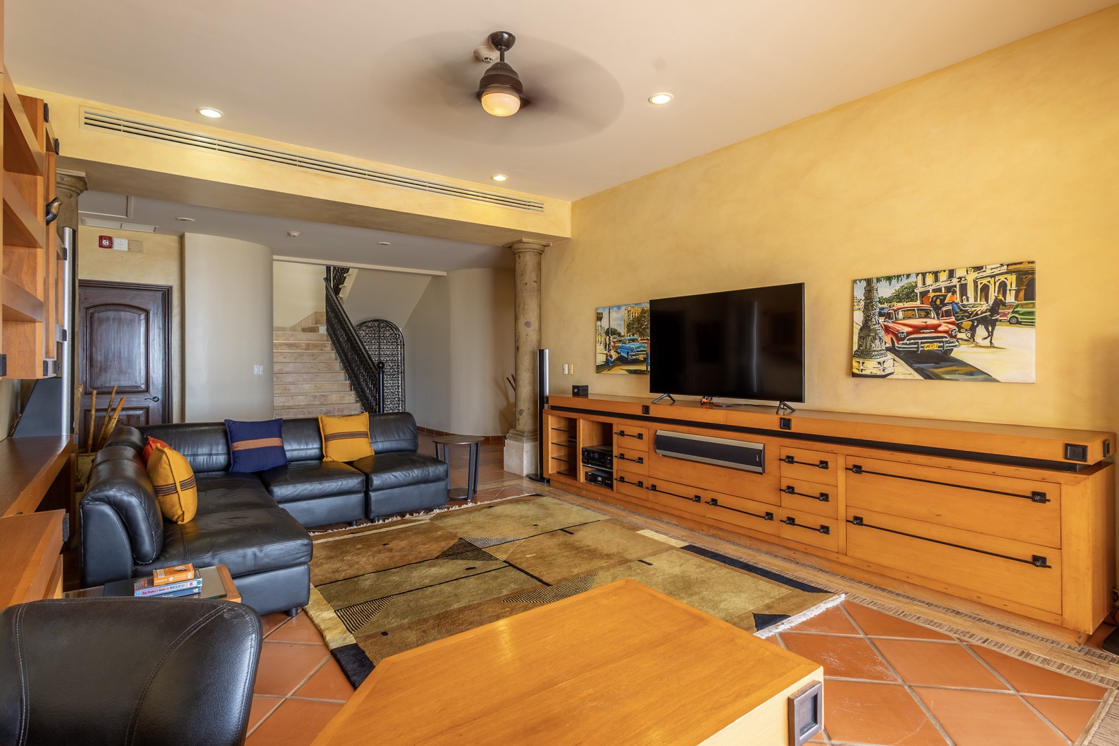 Sink into plush leather sofas and enjoy movie nights in this spacious living area, complete with stylish entertainment center, cozy furnishings, and artistic touches that make you feel right at home.