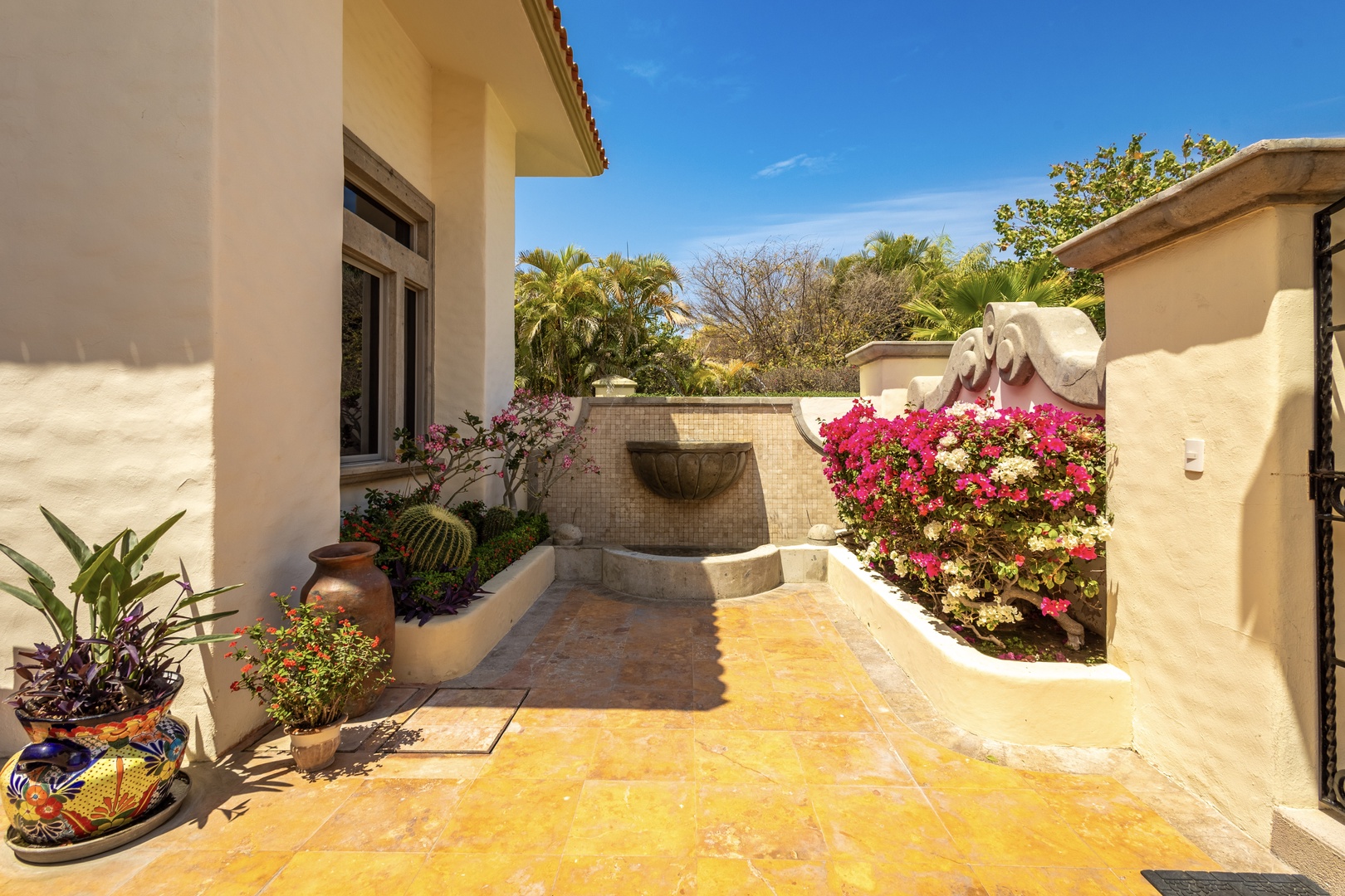 Surrounded by palm trees and vibrant blooms, this private courtyard with its decorative fountain creates a peaceful retreat for relaxation and sunshine.
