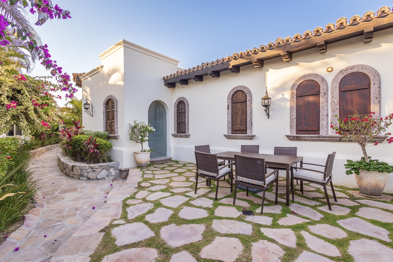 A charming Spanish-style courtyard welcomes you with vibrant bougainvillea, arched doorways, and a dining area where you can savor meals surrounded by tropical gardens.
