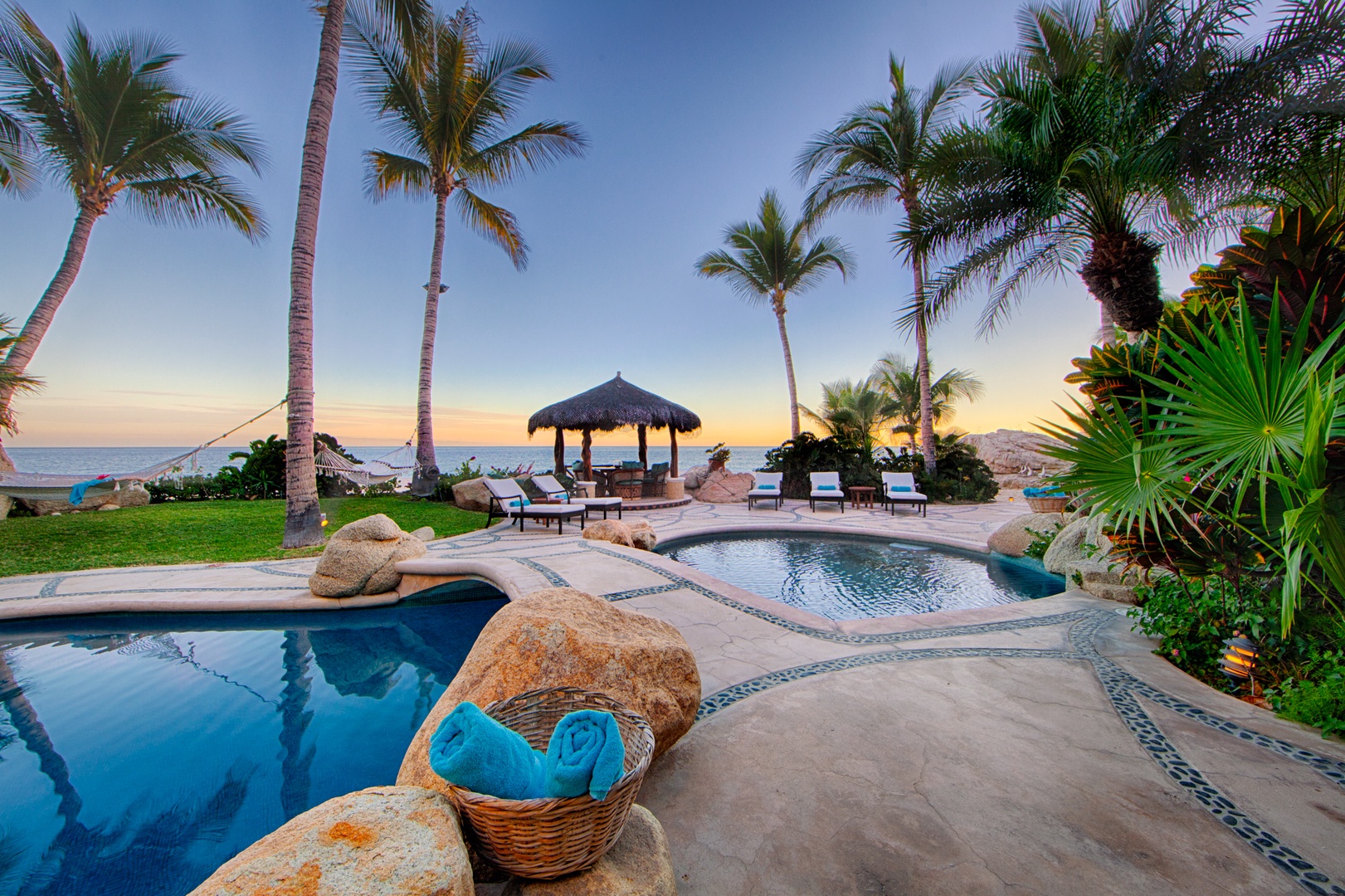 Tropical paradise with private pools, beach access, and thatched-roof palapa surrounded by swaying palms and pristine coastline.