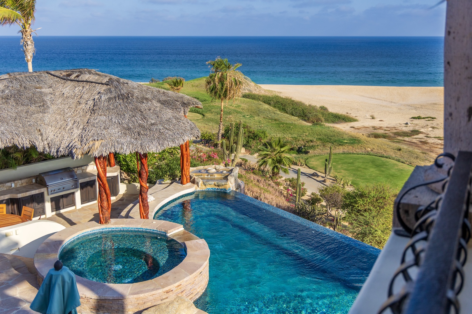 Overlooking a luxurious private pool, hot tub, and beachside palapa just steps from the golden sand and sparkling turquoise ocean.