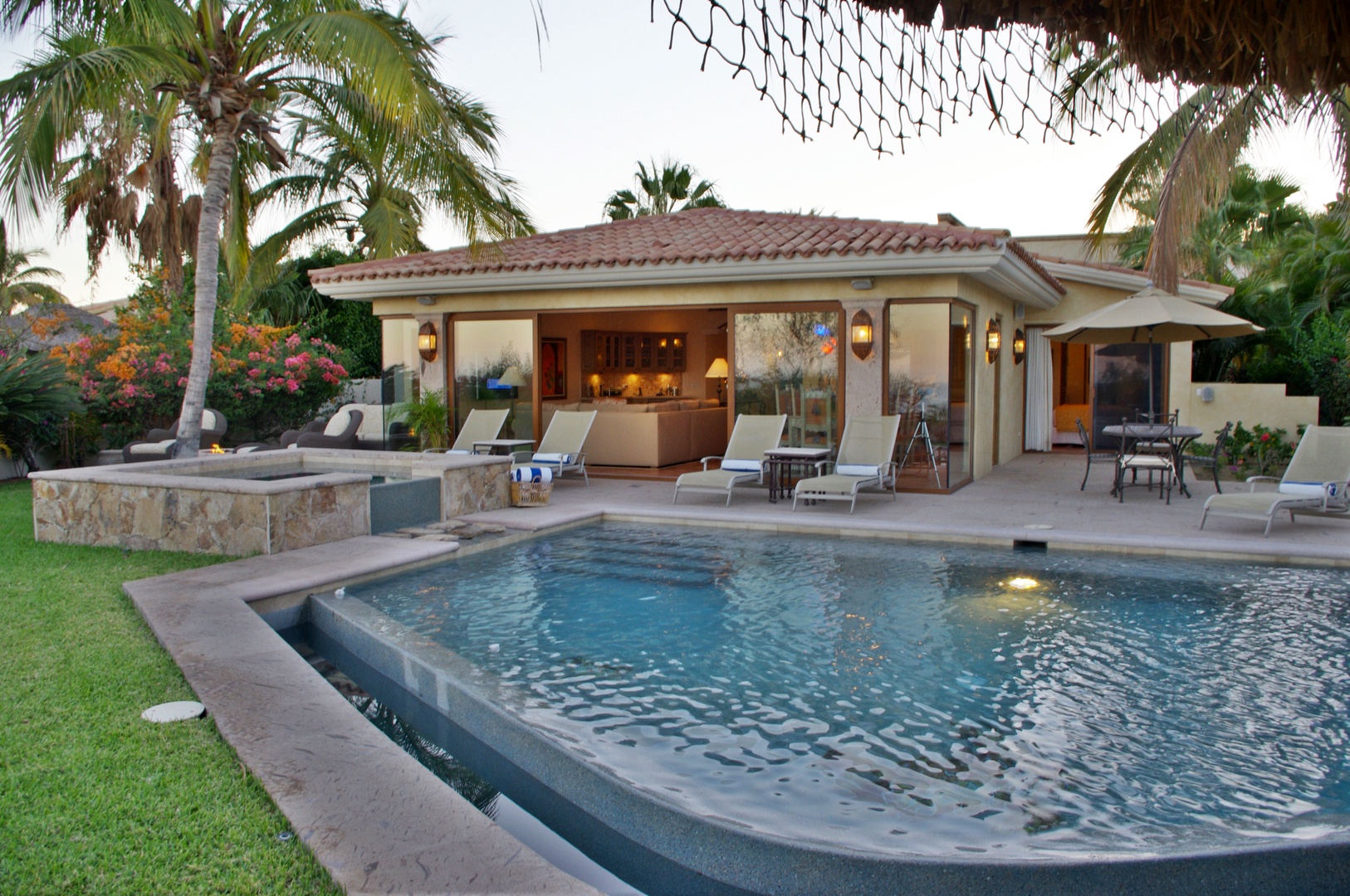 A private Mediterranean-style villa with a sparkling pool, lush palm trees, and spacious lounge areas awaits your perfect tropical escape.