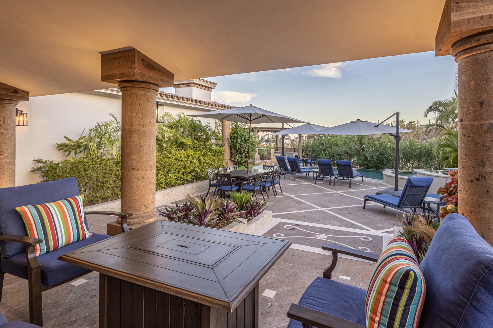Relax under elegant stone columns on your covered patio, with plush seating, a custom shuffleboard court, sparkling pool, and lush tropical gardens just steps away.