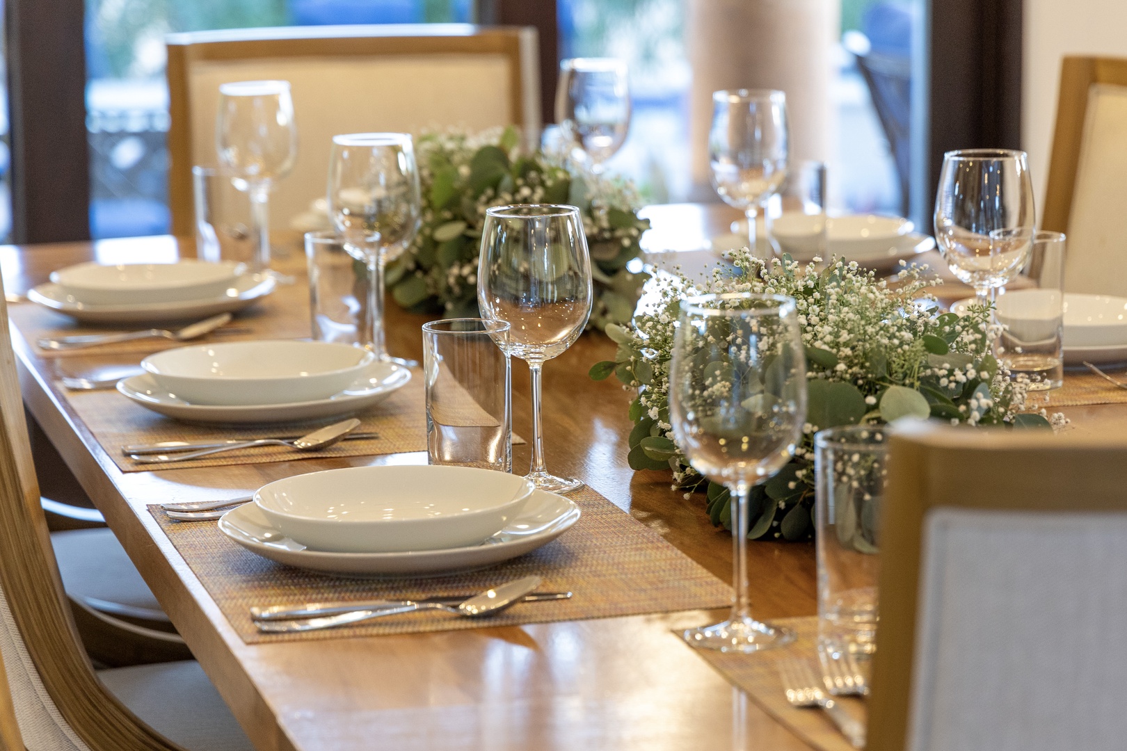 Picture yourself gathering around this beautifully set dining table, where delicate white blooms and sparkling stemware await your memorable meals together.