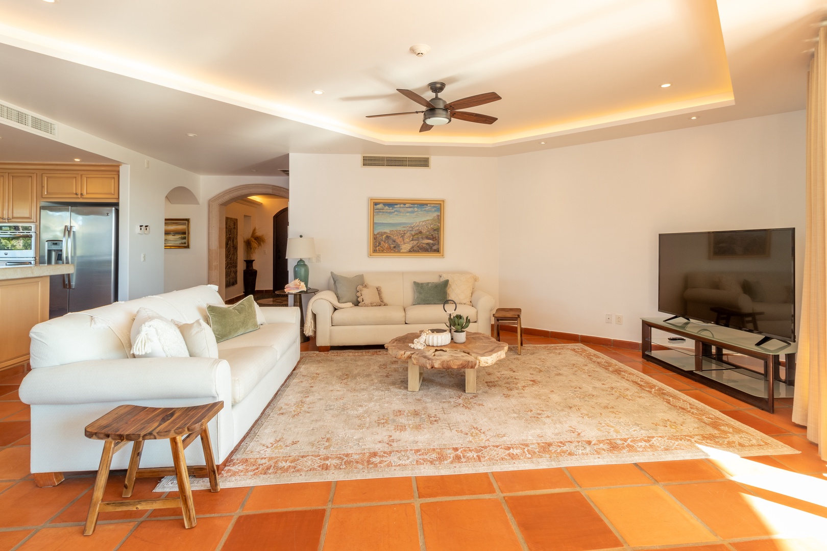Sink into plush sofas under warm cove lighting as ocean breezes drift through your open-concept living space, where natural wood accents and terracotta tiles create a serene coastal retreat.