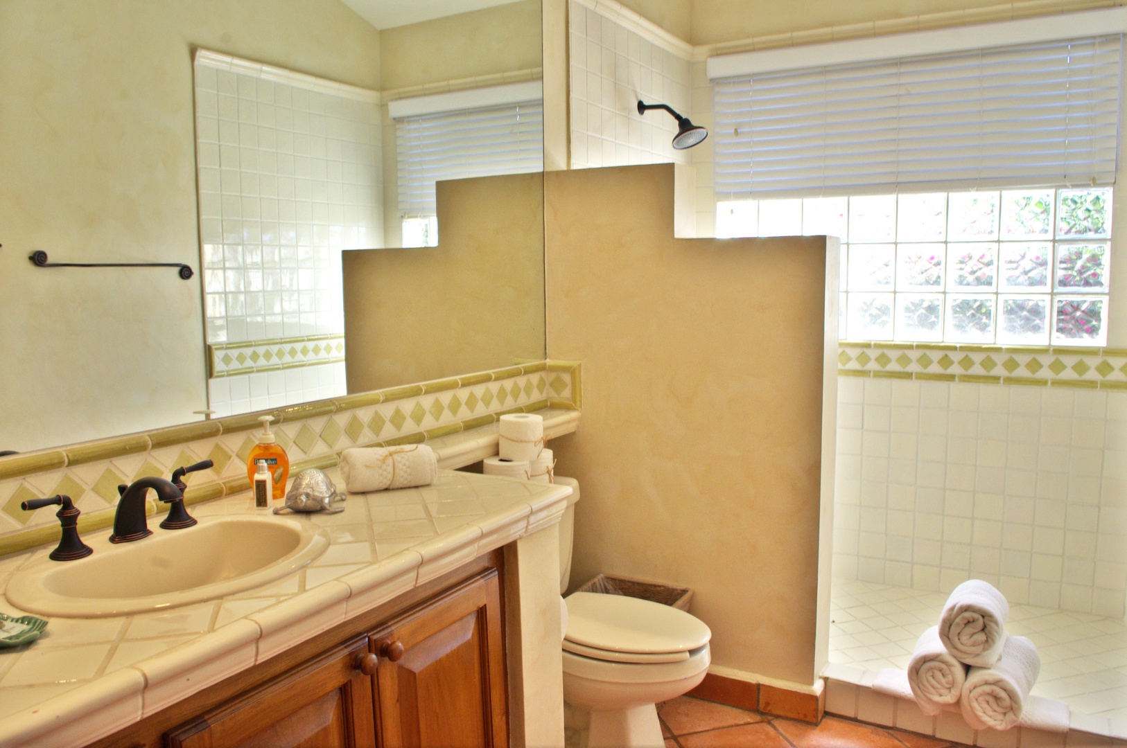 Your private bathroom features a walk-in shower, crisp white tile, and fresh towels ready for your arrival. Natural light brightens the space, making every morning feel refreshing.