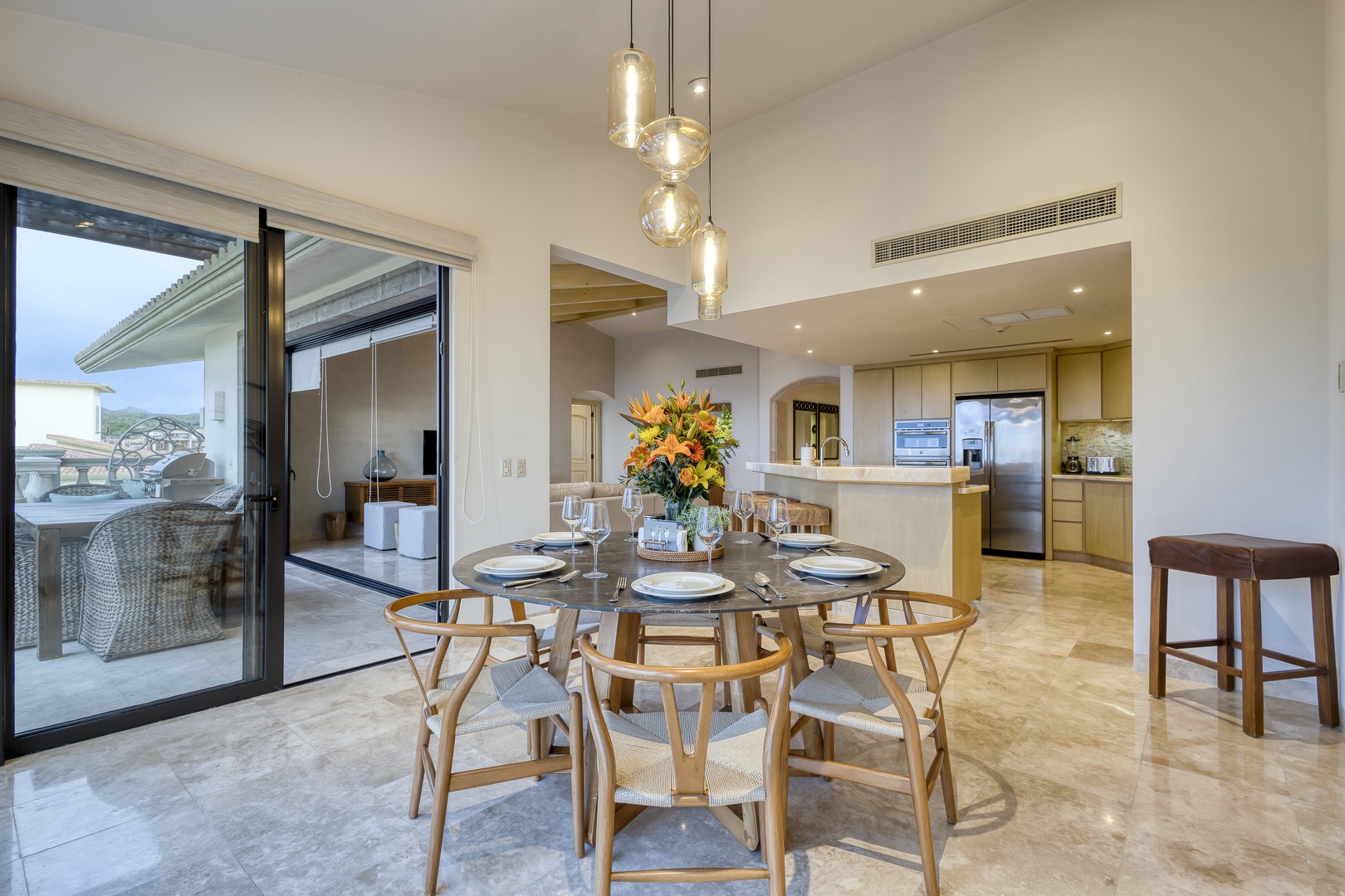 Gather around your elegant dining table where coastal-inspired pendant lights and fresh flowers set the scene for memorable meals with loved ones.
