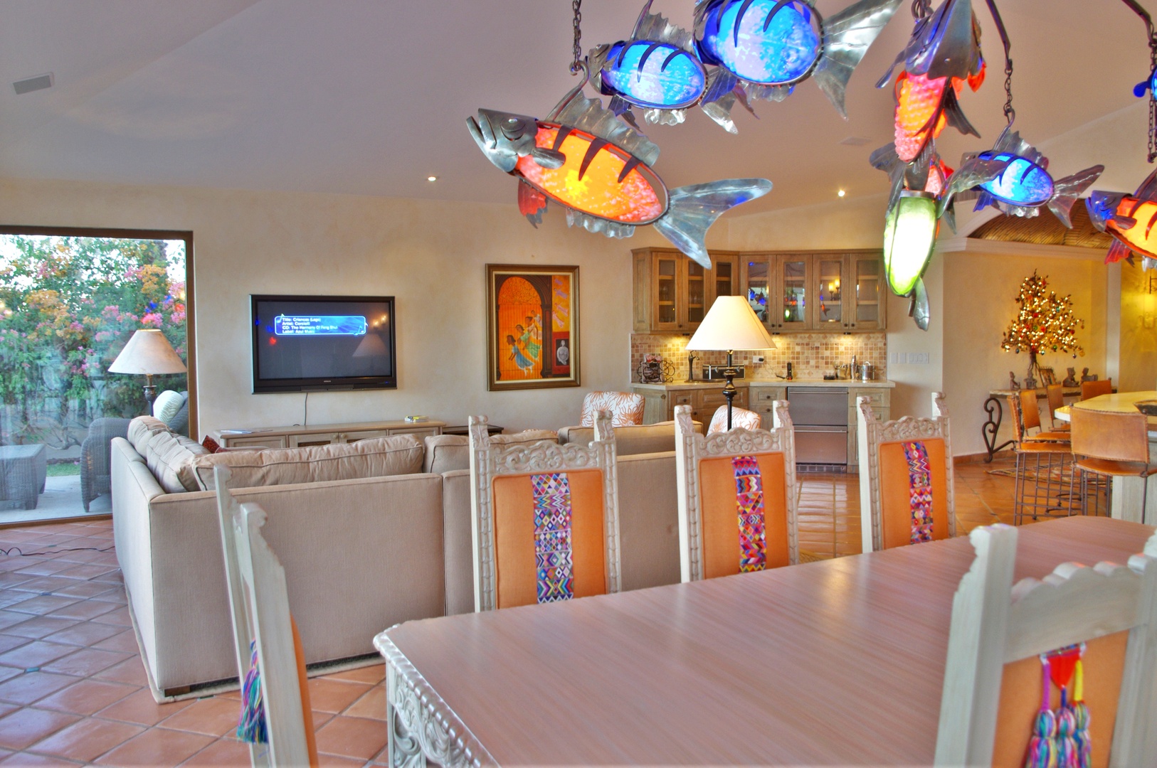 Vibrant handmade fish sculptures float above your open-concept living and dining area, bringing color and personality to your vacation home. Gather for meals or relax with garden views streaming in.