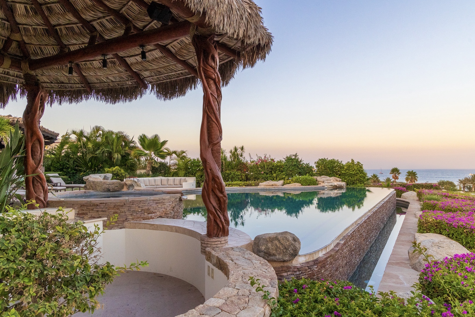 Paradise awaits at this stunning pool area framed by tropical palms and vibrant bougainvillea, with tranquil ocean views stretching beyond the lush garden.