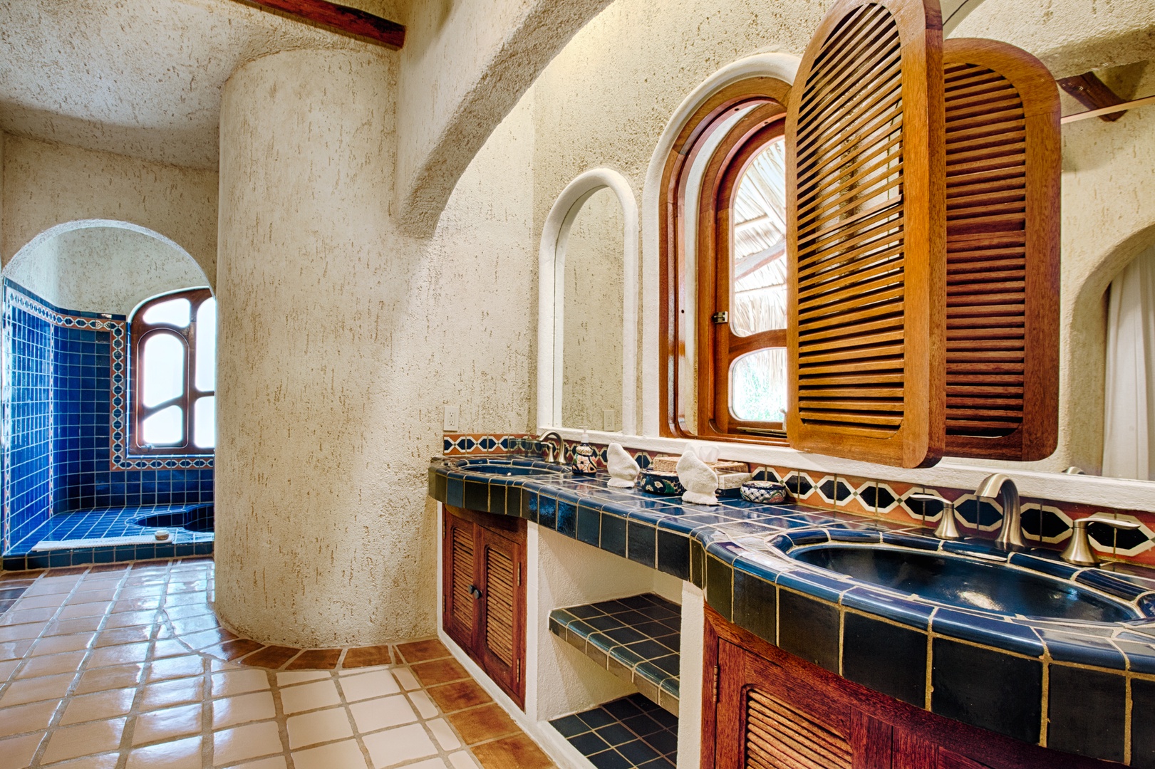 Step into your stunning ensuite bathroom featuring handcrafted Mexican tilework and elegant arched doorways that create a spa-like sanctuary for your morning routine.