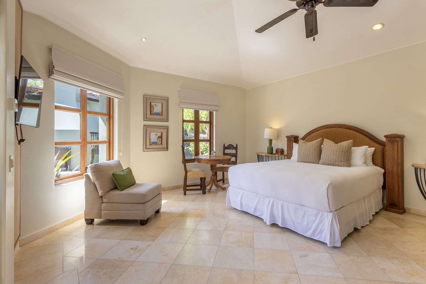 Unwind in your serene bedroom featuring a plush king bed, cozy reading chair, and warm natural light streaming through large windows.