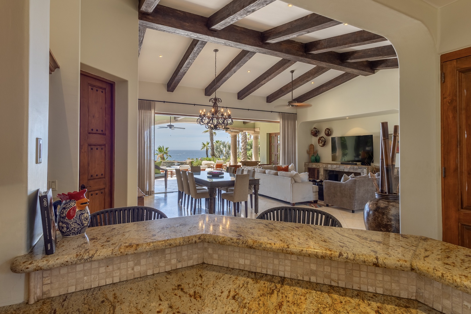 Your gourmet kitchen flows seamlessly into elegant living spaces, where exposed beams frame ocean views and luxury awaits.