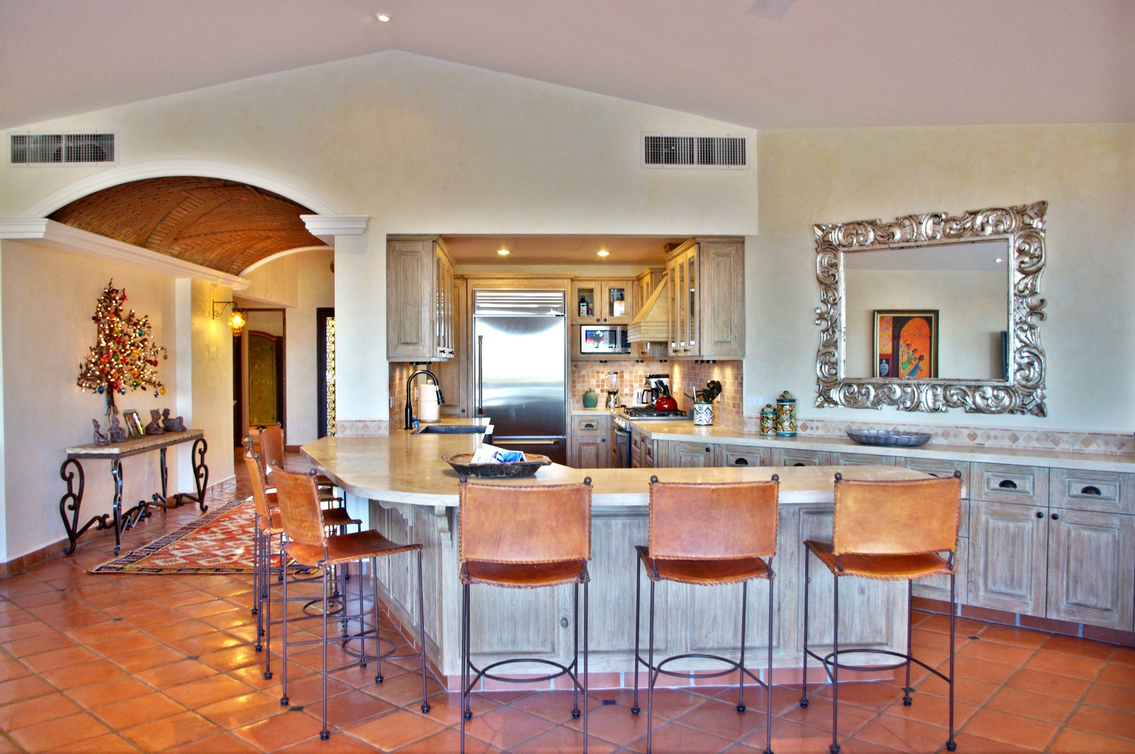 Gather with loved ones in your open-concept kitchen and dining area, featuring rustic terracotta floors, elegant arched doorways, and a spacious island perfect for morning coffee or evening meals.