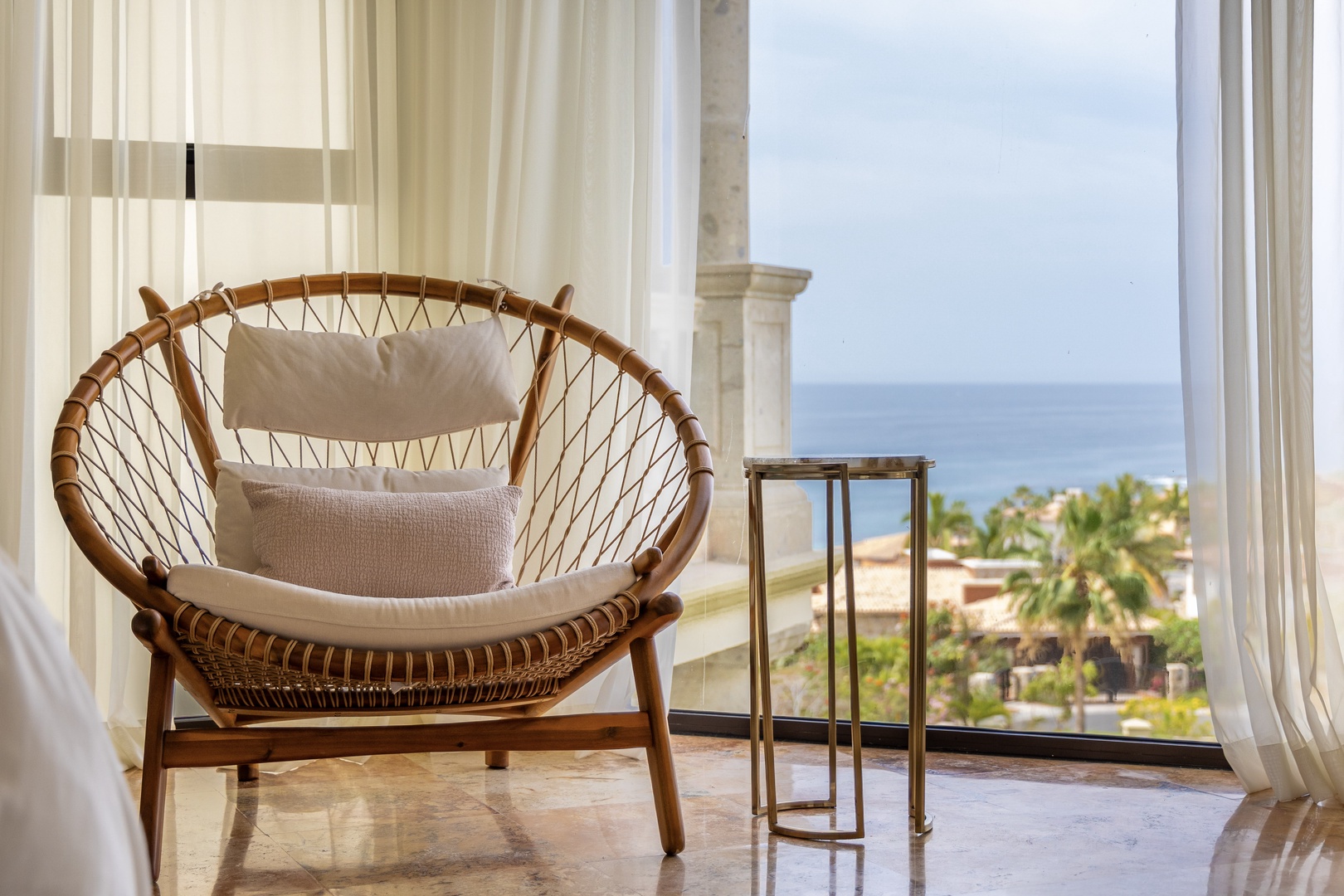 Sink into your private wicker chair and soak up stunning ocean views through floor-to-ceiling windows—your perfect retreat awaits.