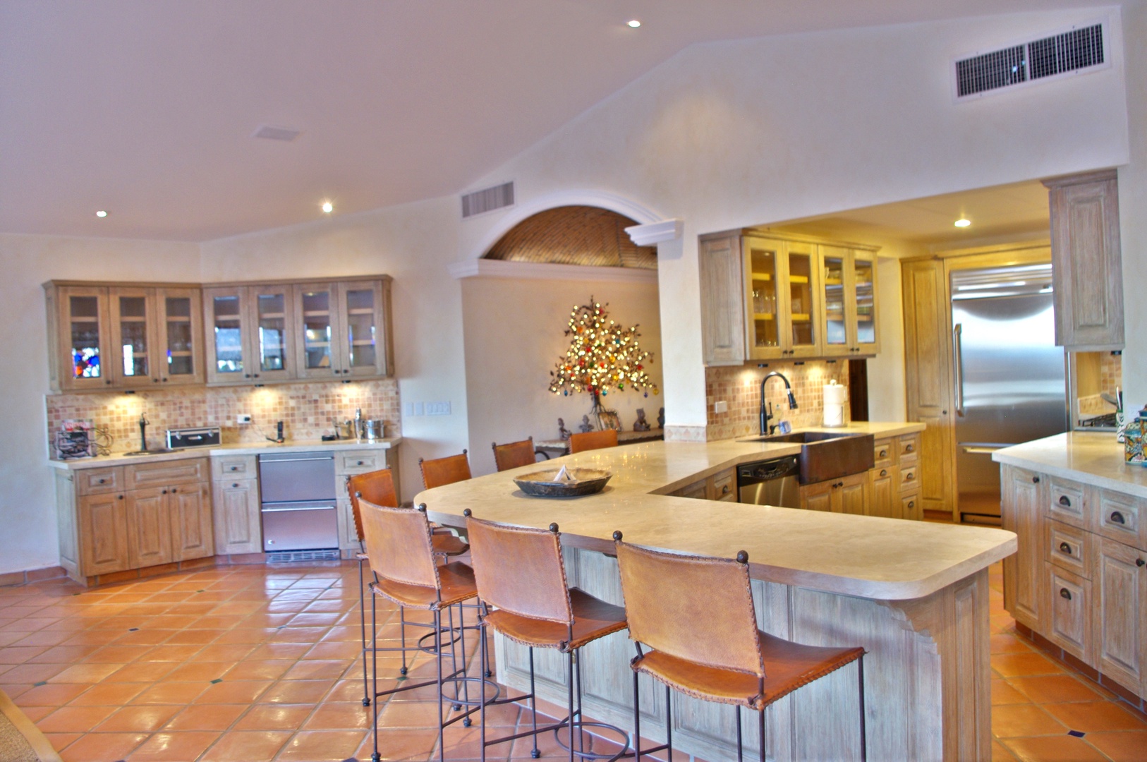 This spacious chef's kitchen offers everything you need to prepare meals together—with generous counter space, dual islands, and abundant cabinetry. The warm tile floors and elegant archways add timeless charm to your culinary experience.