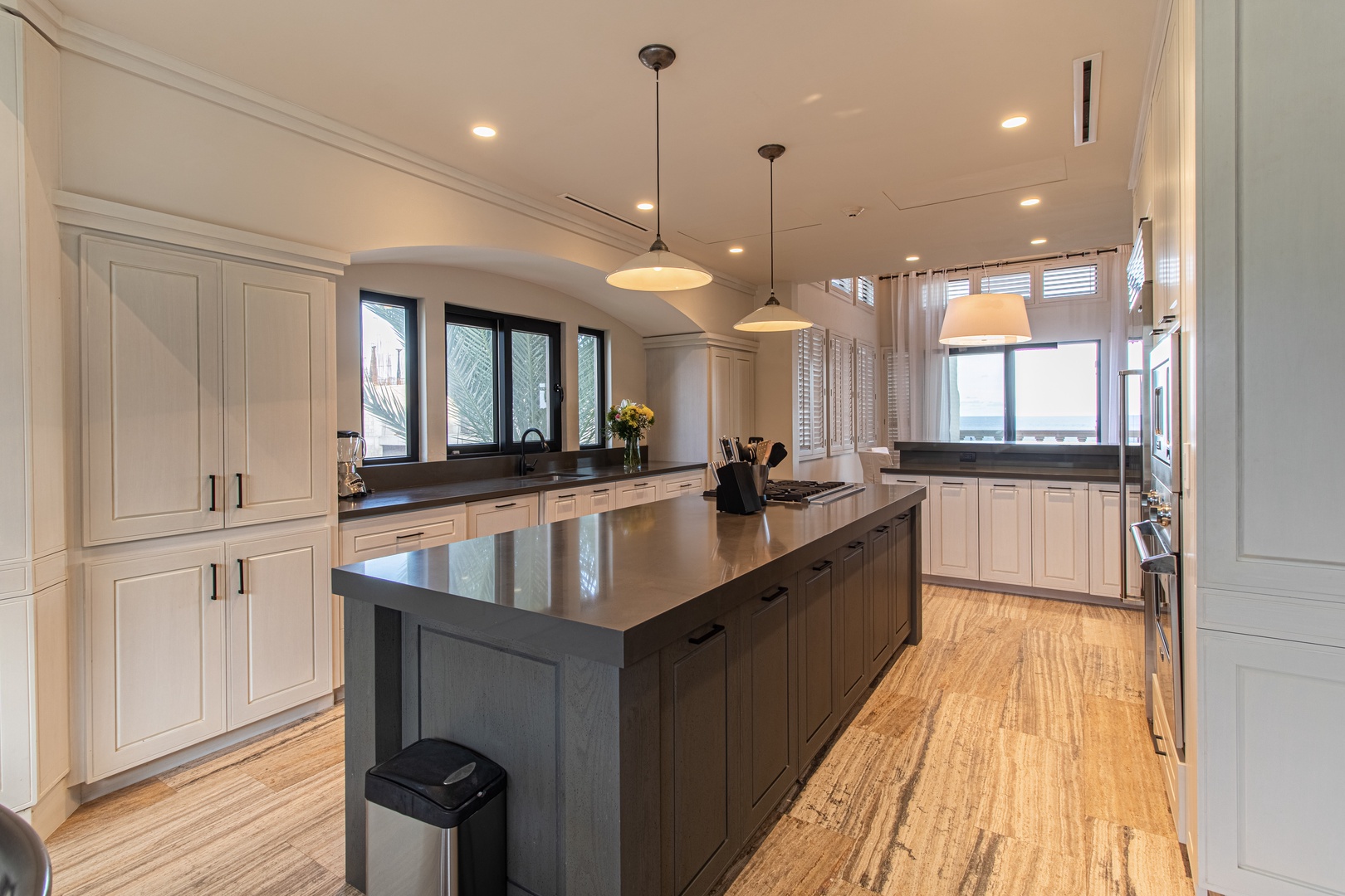 Step into your fully equipped chef's kitchen with elegant white cabinetry, sleek granite island, and modern appliances bathed in natural light from expansive windows.