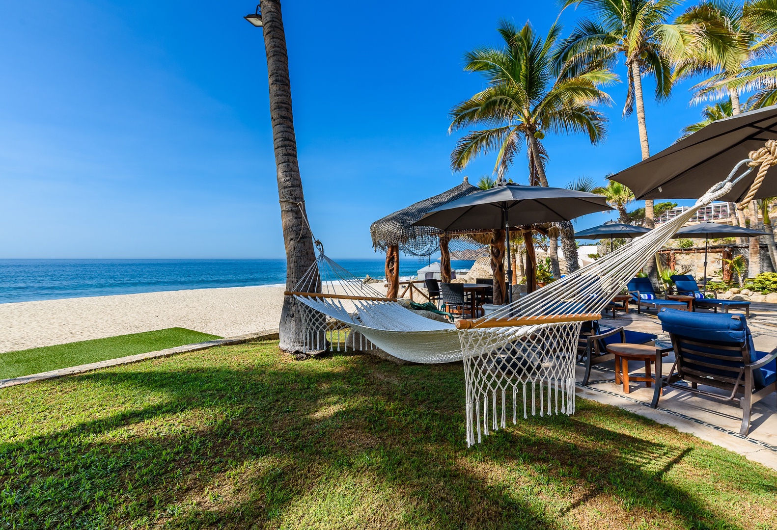 Beachfront paradise with a hammock swaying beneath palm trees, just steps from turquoise waters and private thatched cabana, perfect for sunny afternoons and ocean breezes.