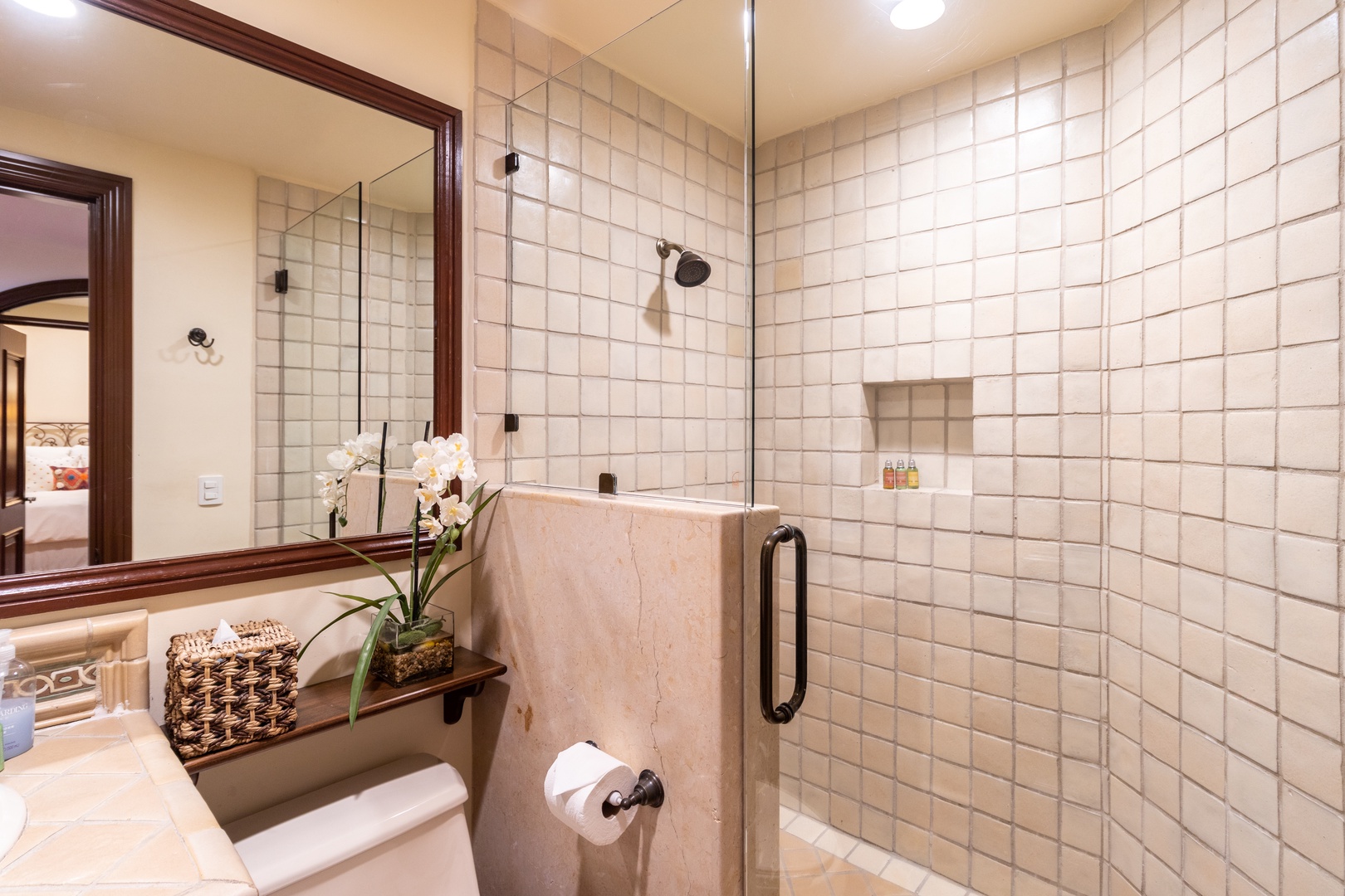 Step into your private bathroom sanctuary with a spacious walk-in shower, elegant tile work, and thoughtful touches like fresh orchids to make your stay feel special.