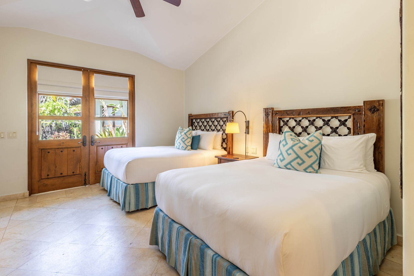 Your twin bedroom offers crisp linens, handcrafted headboards, and garden views through charming wooden doors.