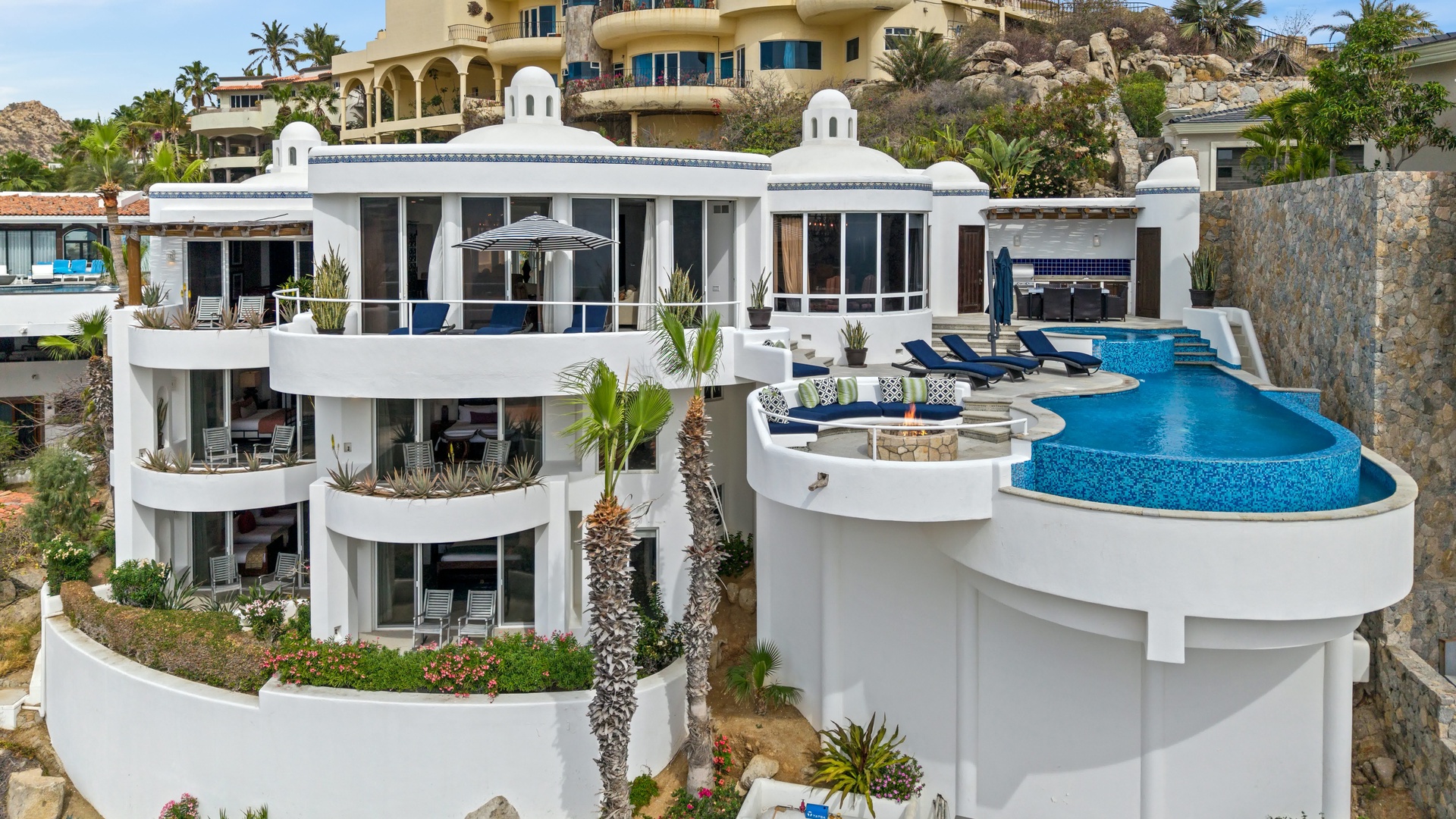 Stunning white villa cascades down the hillside with infinity pool and tropical landscaping creating the perfect luxury escape.