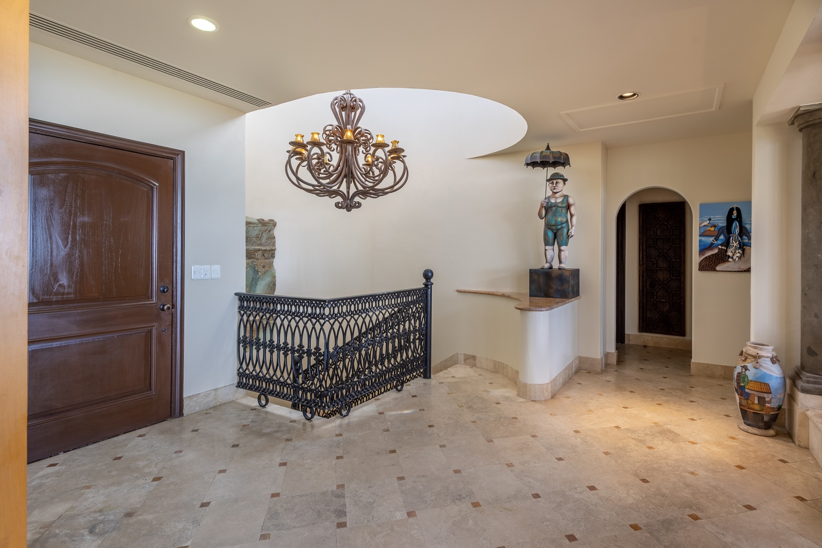 The entrance welcomes you with elegant decor, showcasing unique art pieces and an ornate chandelier that sets the tone for your stay. The spacious entryway features beautiful stonework floors and tasteful furnishings.