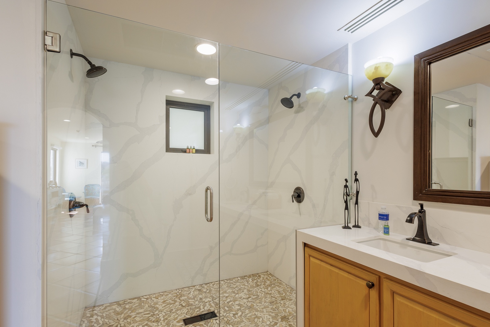 Refresh yourself in this modern bathroom with a spacious walk-in shower featuring dual showerheads and sleek marble-style walls, paired with a polished vanity for your comfort.