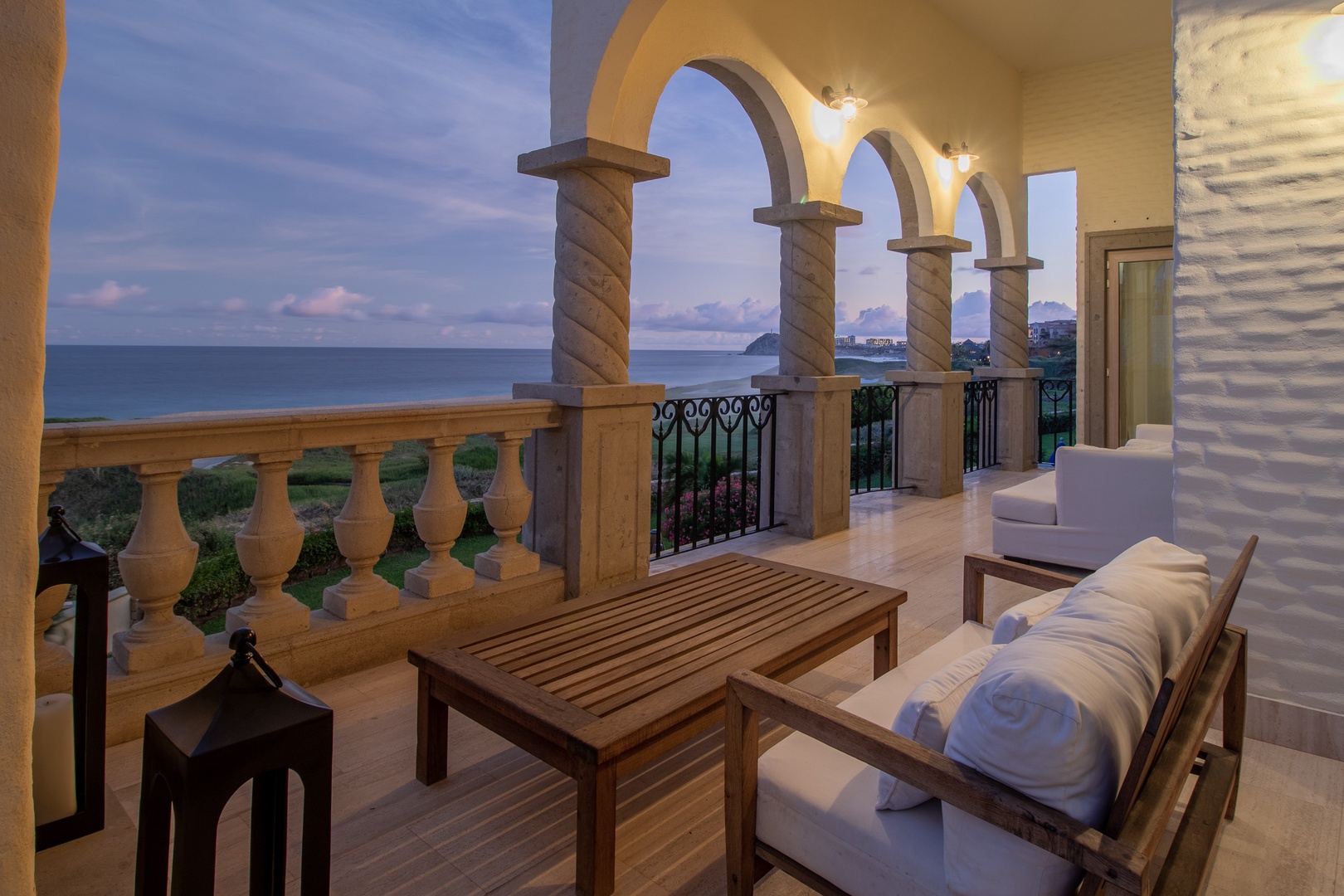 Stunning beachfront terrace where sweeping ocean views meet elegant arched architecture, inviting you to unwind in ultimate comfort as the day transitions to evening.