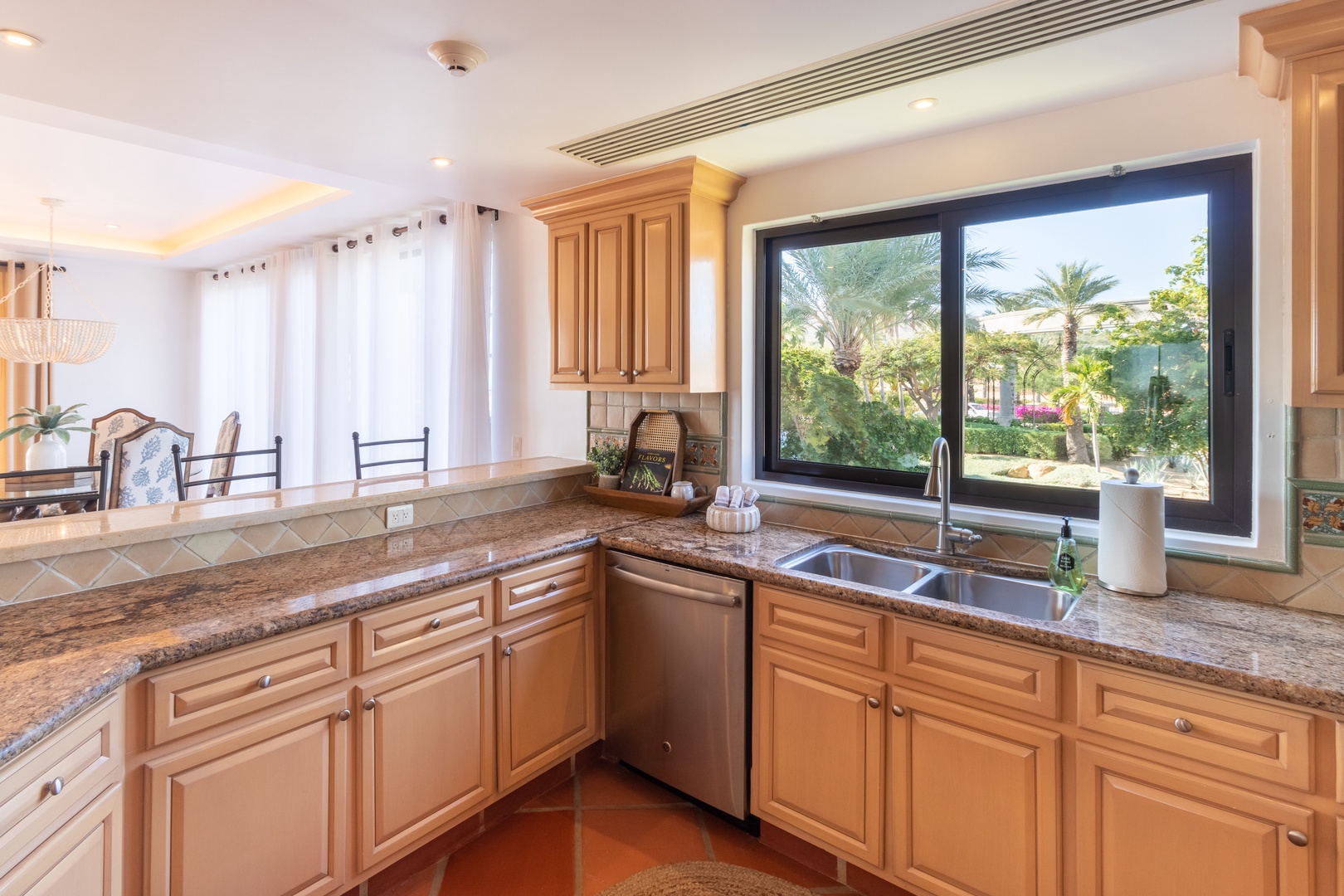 Cook with ease in this bright, fully equipped kitchen featuring granite countertops, modern appliances, and a stunning garden view through large windows.