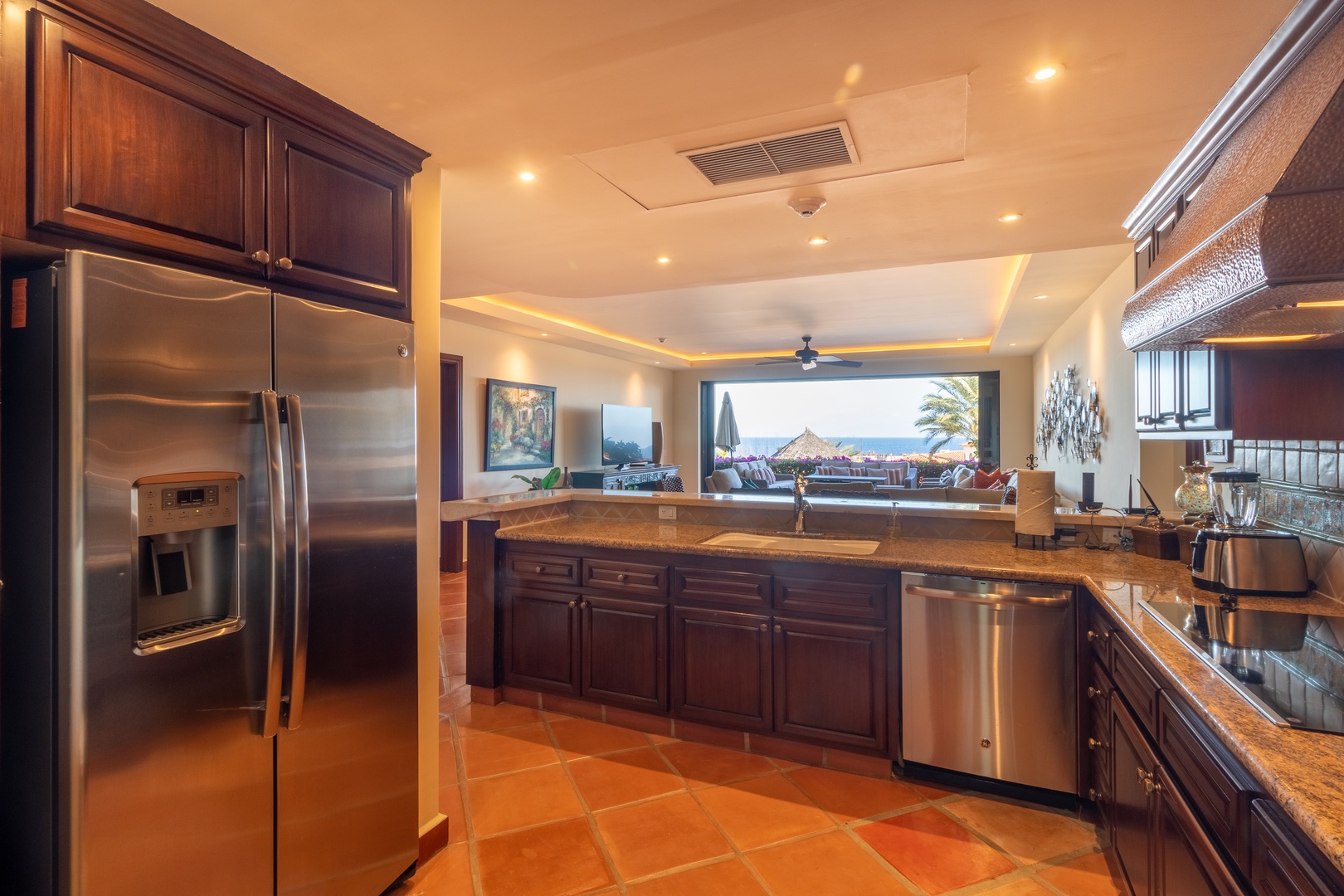 Your gourmet kitchen boasts rich wood cabinetry, granite counters, stainless appliances, and an open flow to the living area with stunning ocean views beyond.