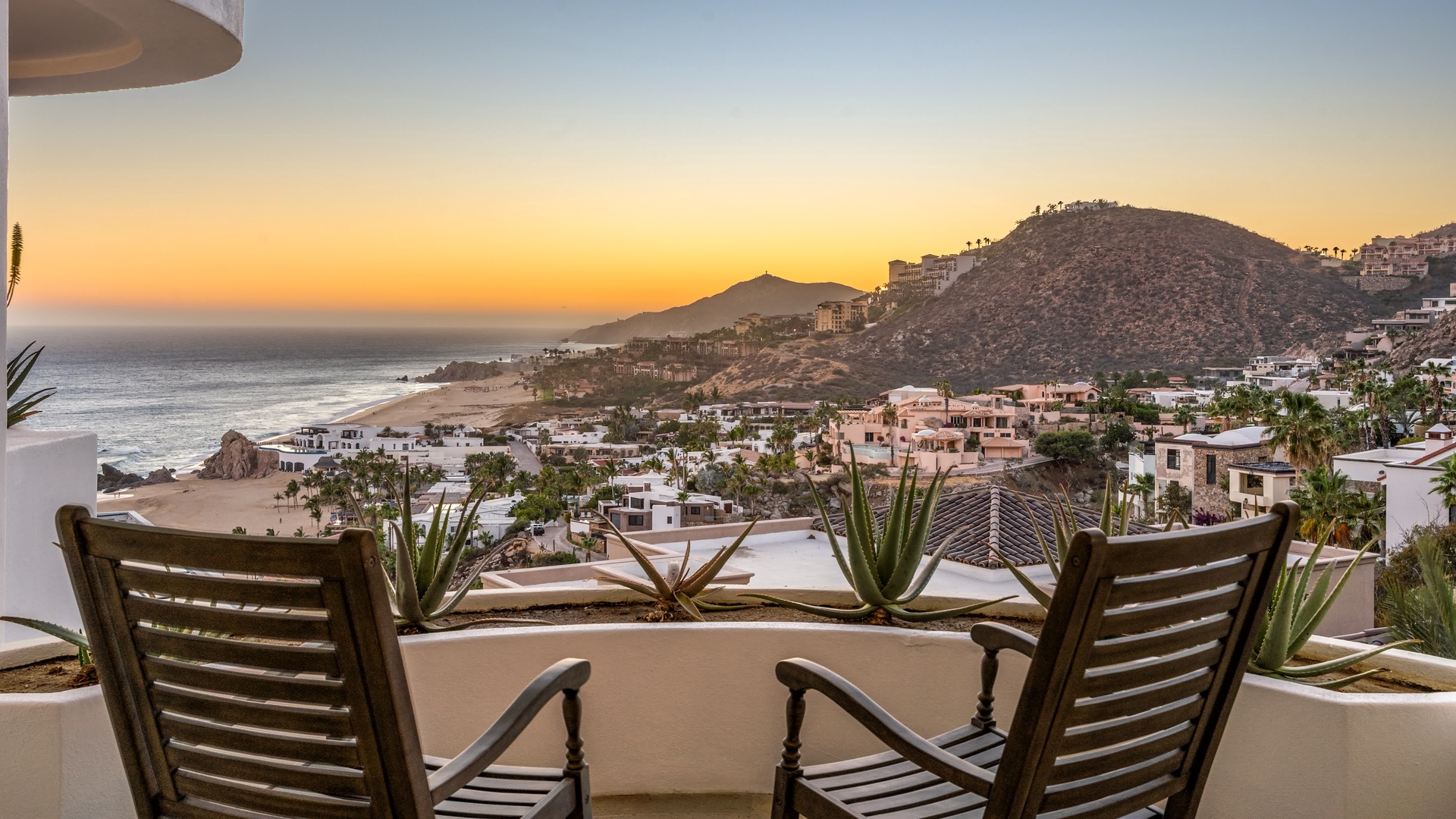 Coastal terrace with panoramic sunset views over hillside community and ocean beach.